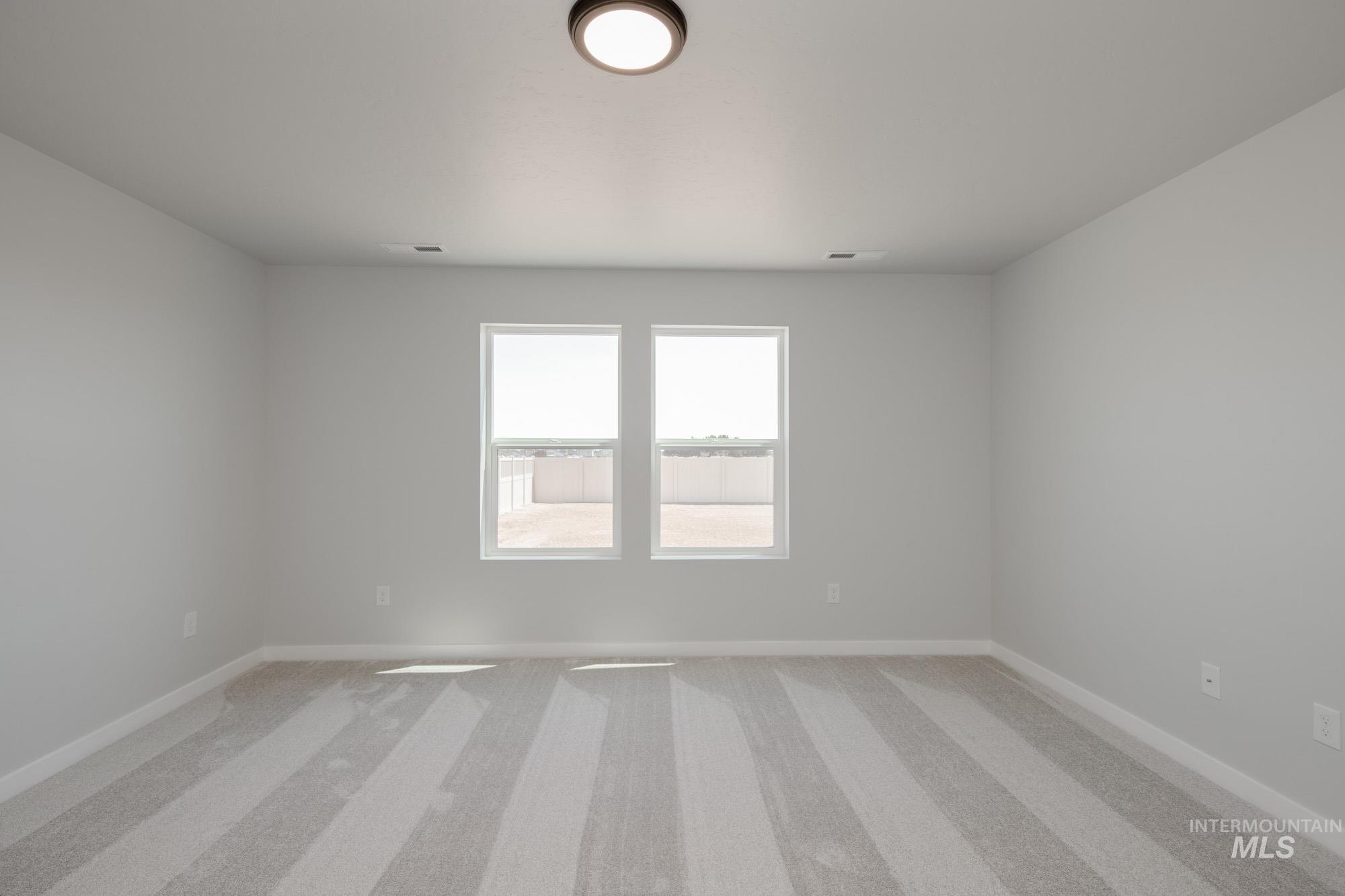 Empty room featuring light colored carpet and baseboards