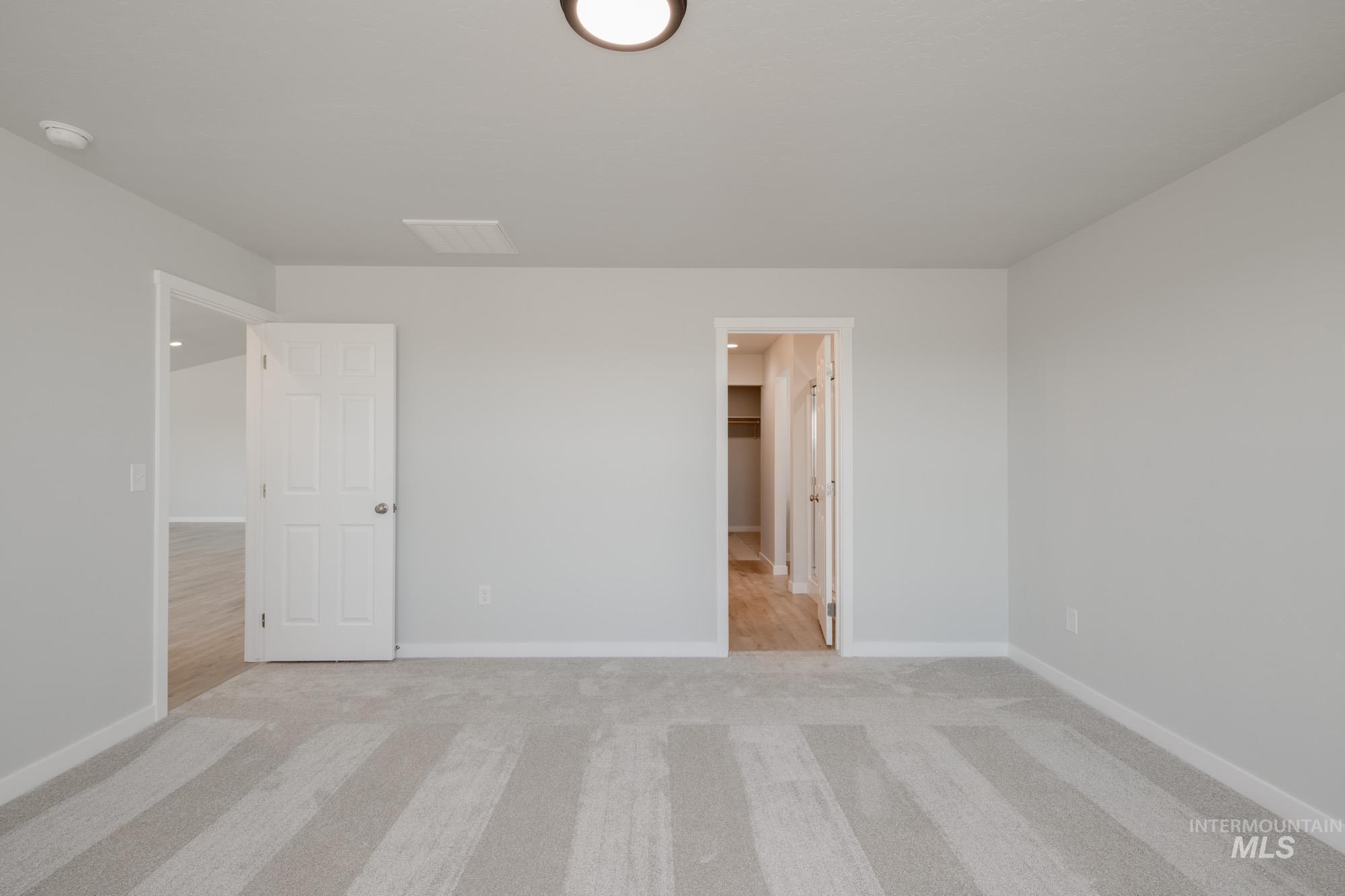 Unfurnished bedroom with light colored carpet and baseboards