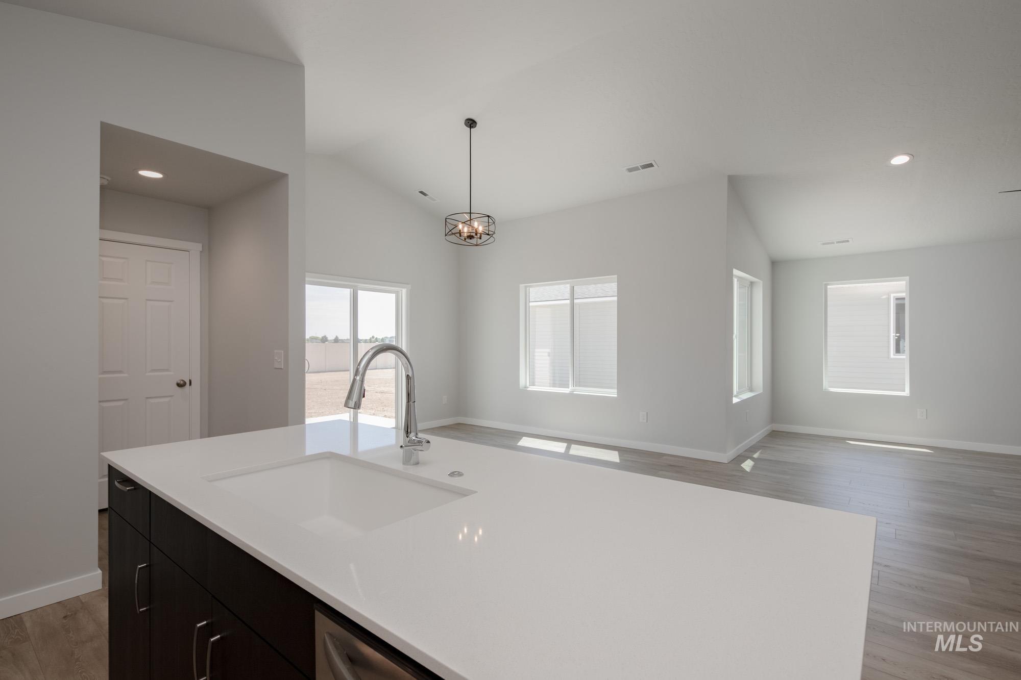 Kitchen with light wood finished floors, recessed lighting, dark cabinets, open floor plan, and decorative light fixtures