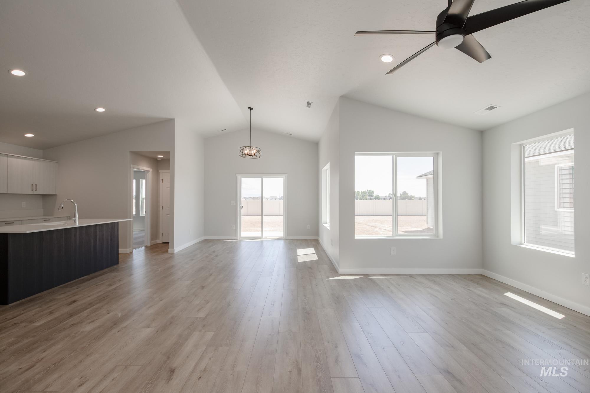 Unfurnished living room featuring plenty of natural light, light wood-type flooring, lofted ceiling, recessed lighting, and a ceiling fan