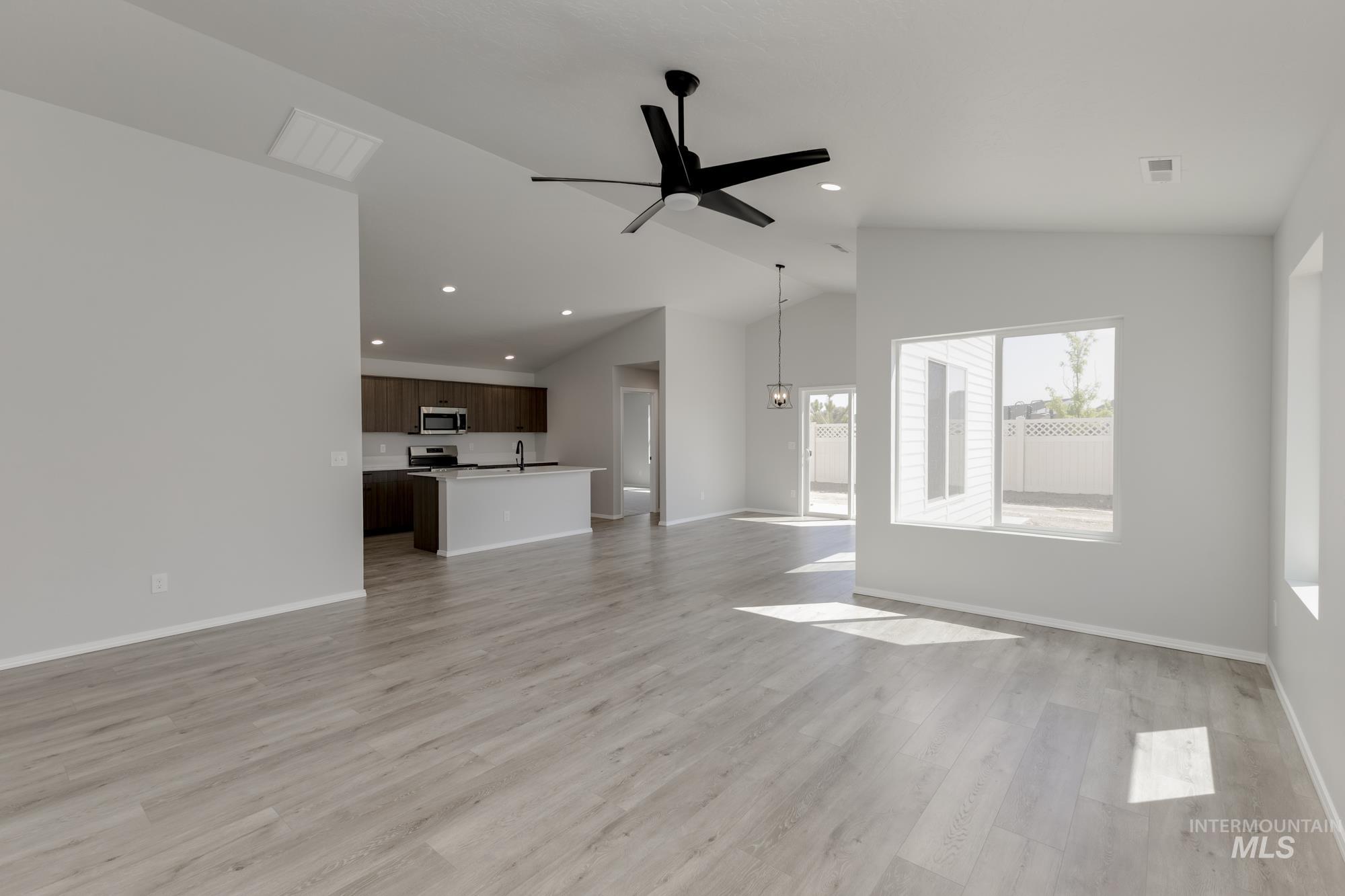 Unfurnished living room featuring ceiling fan, light wood-style flooring, recessed lighting, and high vaulted ceiling
