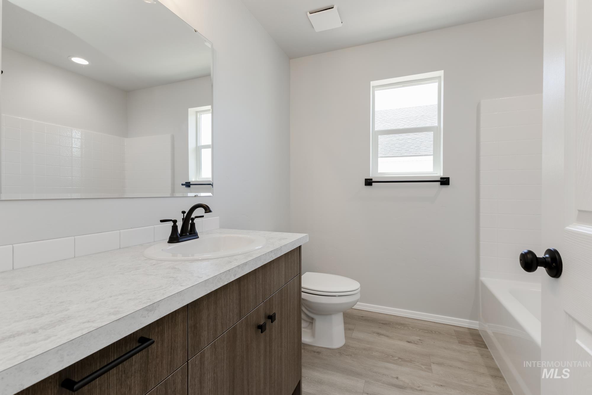 Full bathroom with light wood-style flooring, plenty of natural light, vanity, and bathtub / shower combination