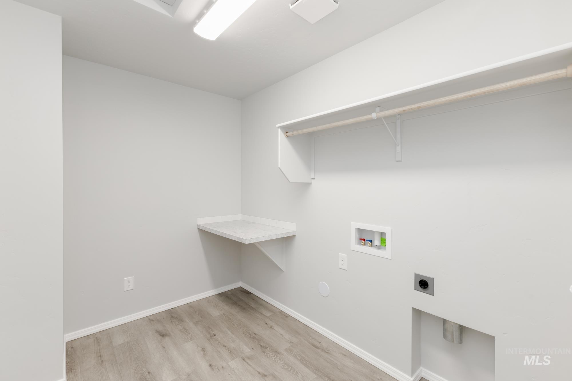 Laundry area with light wood-style floors, washer hookup, and hookup for an electric dryer