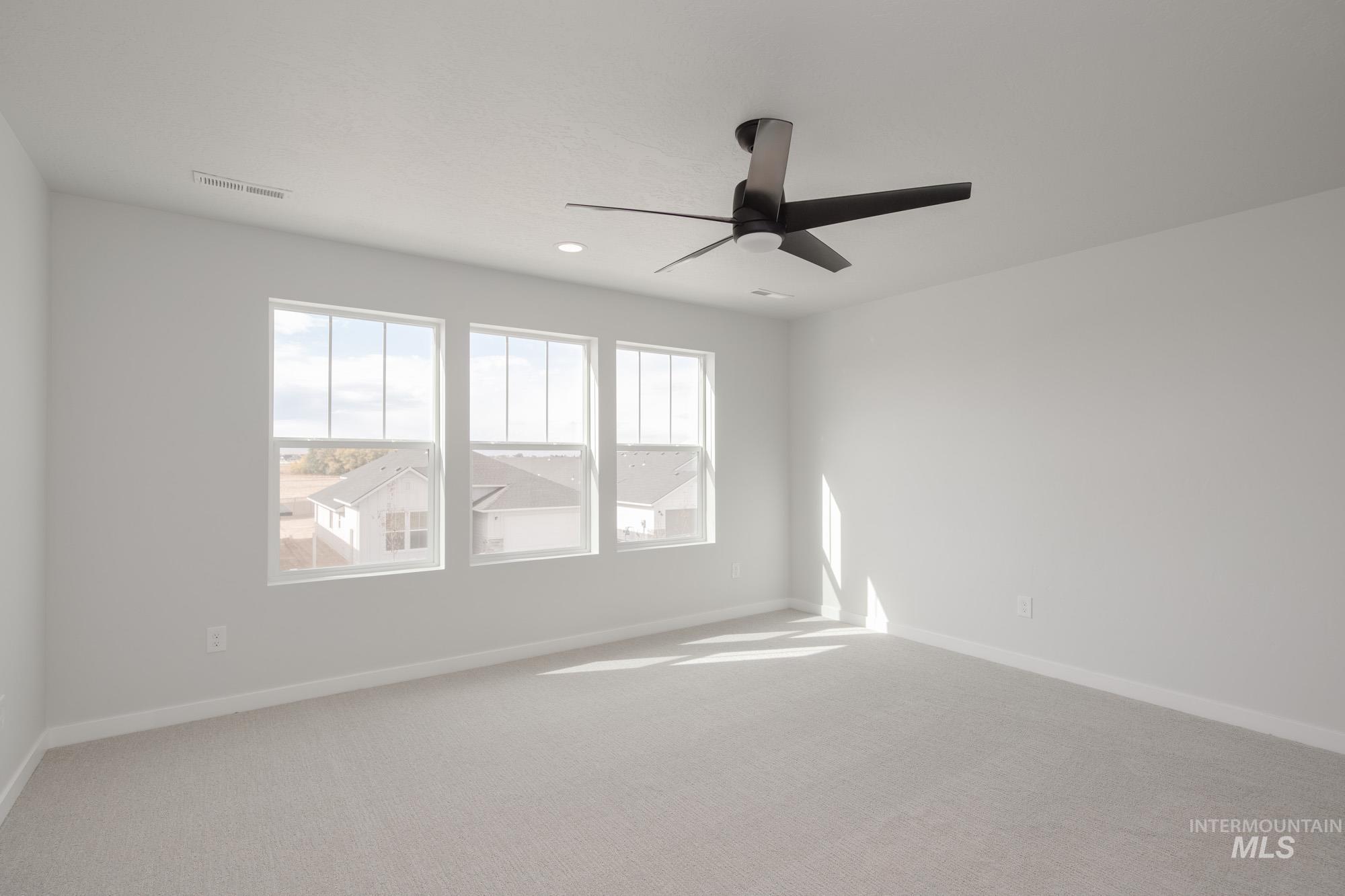 Empty room featuring light carpet, plenty of natural light, ceiling fan, and recessed lighting