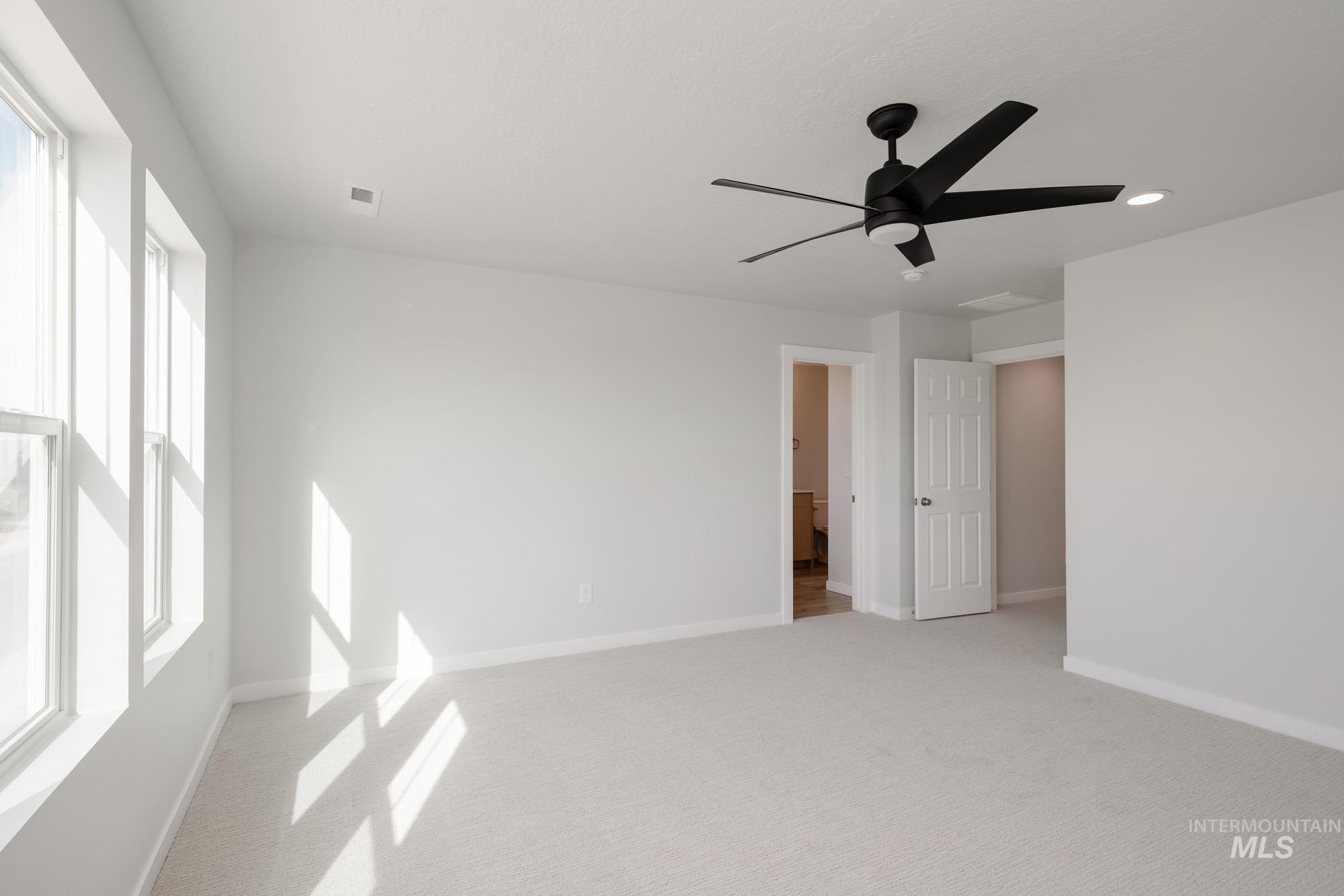 Unfurnished bedroom with light carpet and a ceiling fan