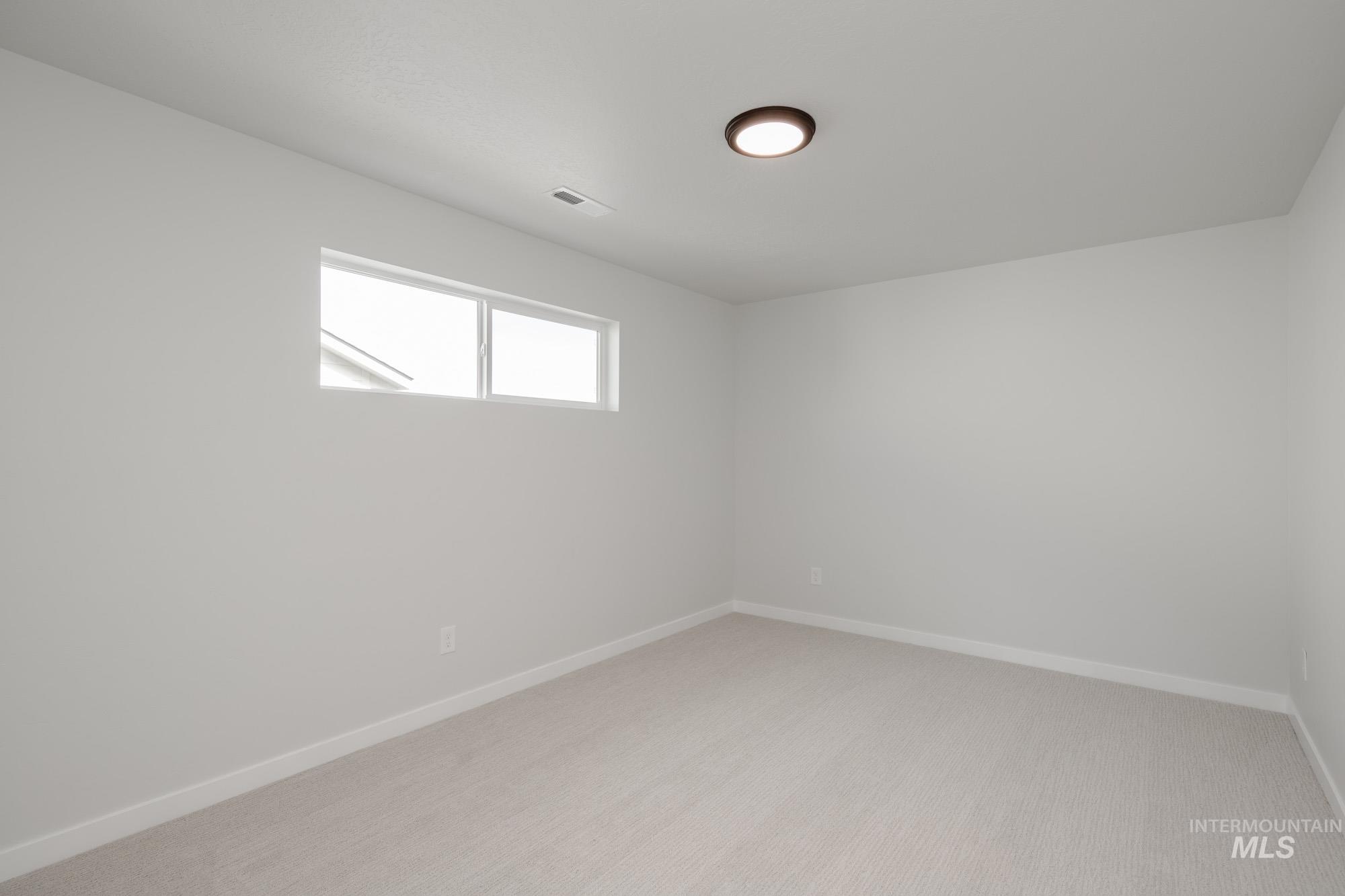 Spare room with light carpet and baseboards