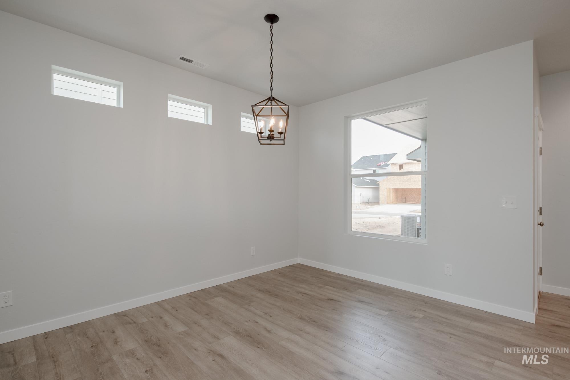 Unfurnished dining area with plenty of natural light, light wood-style floors, and a chandelier