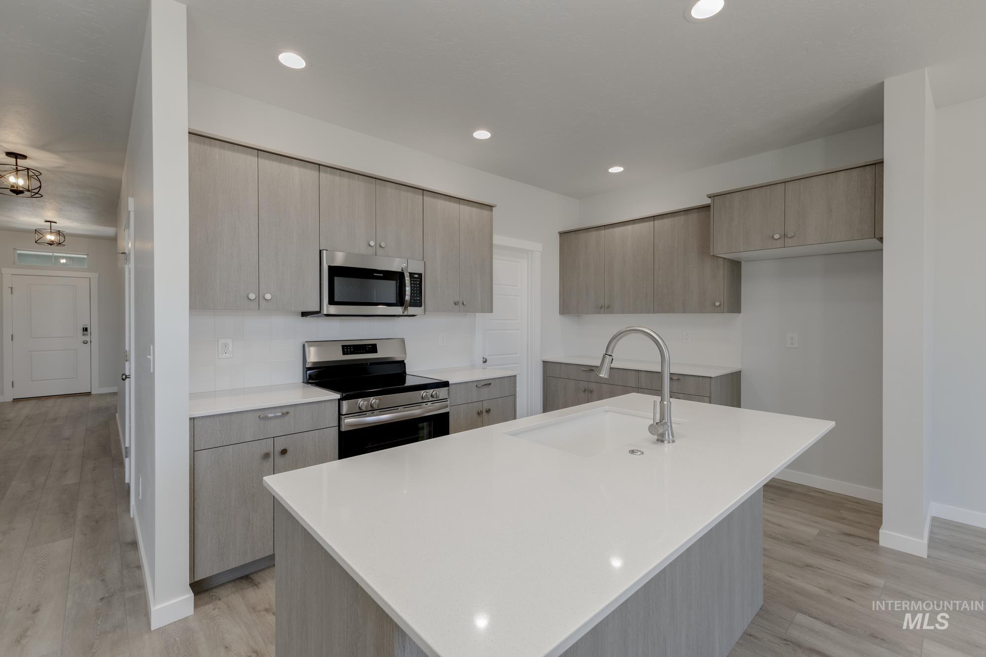 Kitchen featuring stainless steel appliances, modern cabinets, light wood finished floors, recessed lighting, and light stone counters