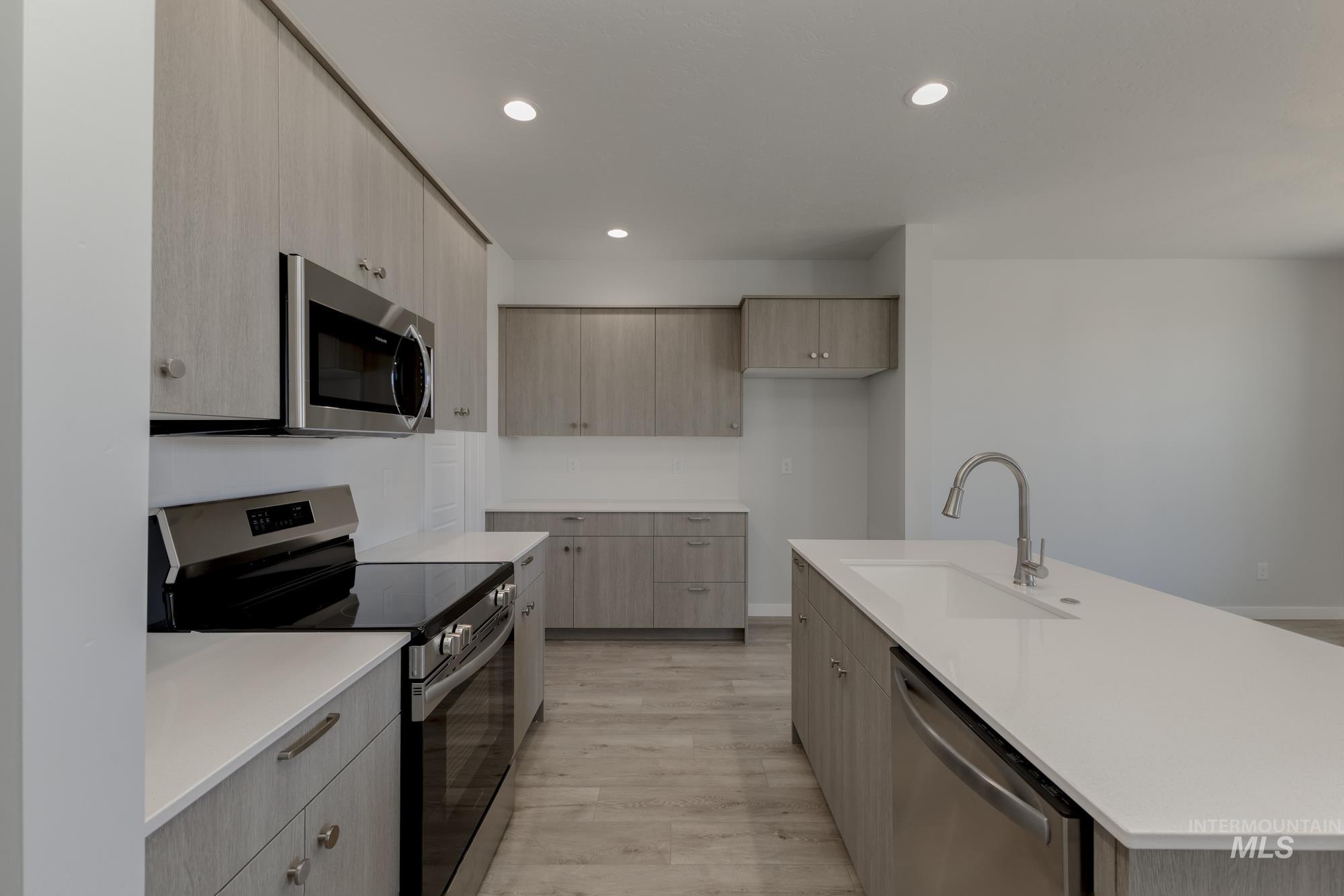 Kitchen with appliances with stainless steel finishes, modern cabinets, recessed lighting, light wood-style flooring, and light brown cabinets