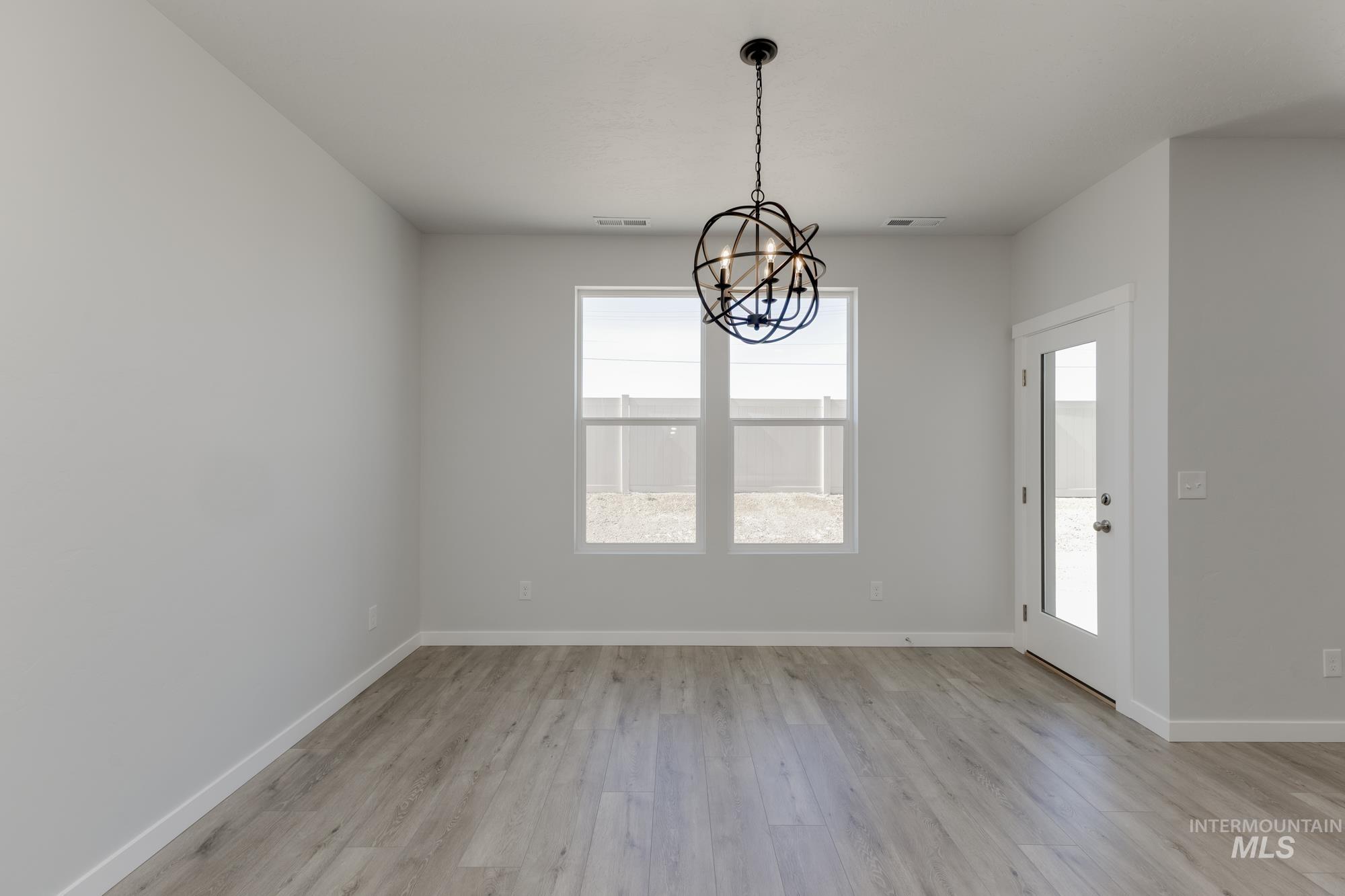 Unfurnished dining area with a chandelier and light wood-style floors