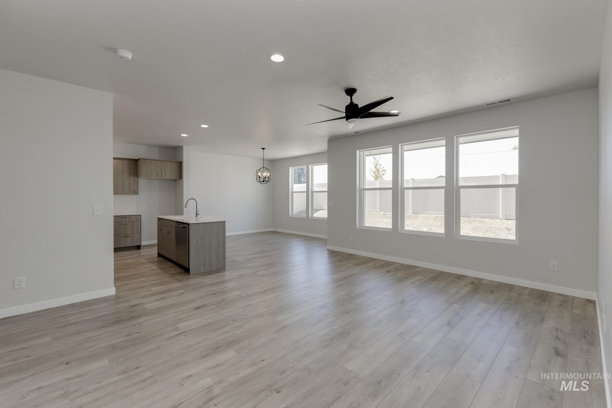 Unfurnished living room featuring recessed lighting, ceiling fan, light wood-type flooring, and a chandelier