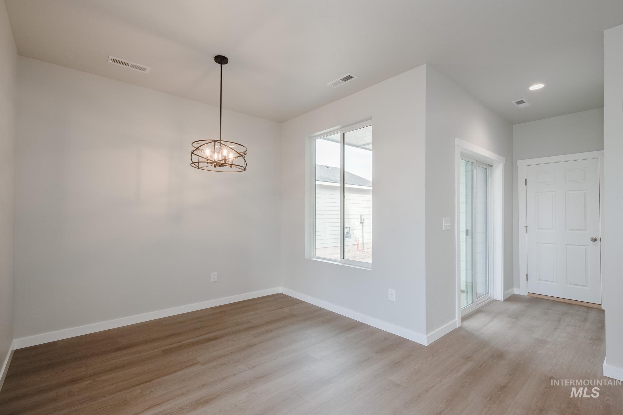 Unfurnished dining area featuring light wood finished floors and a chandelier