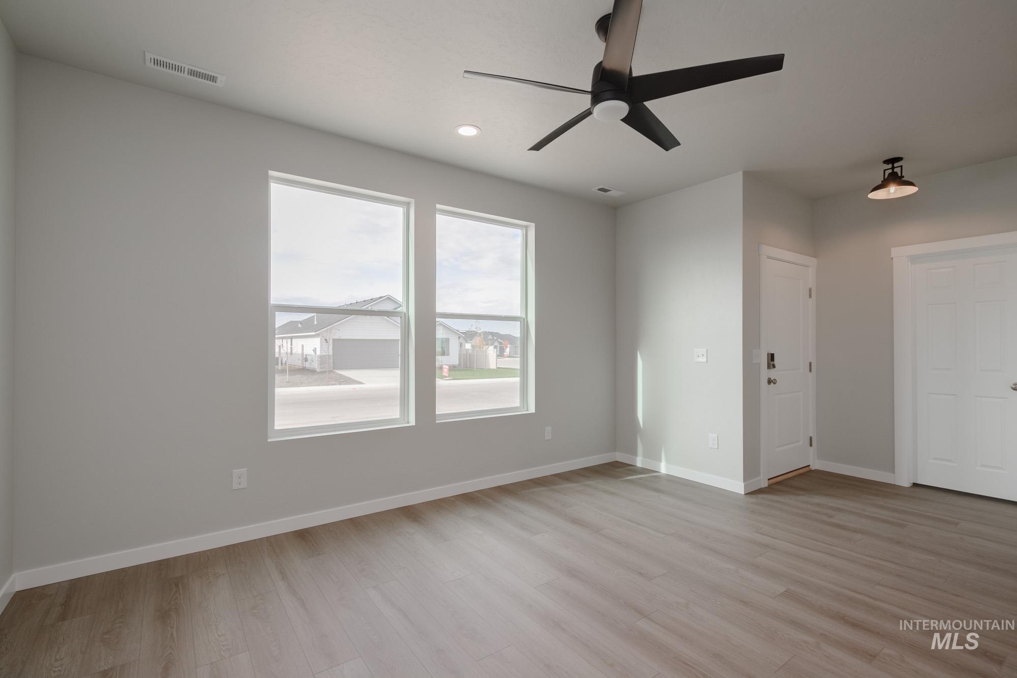 Empty room featuring light wood finished floors, ceiling fan, and recessed lighting