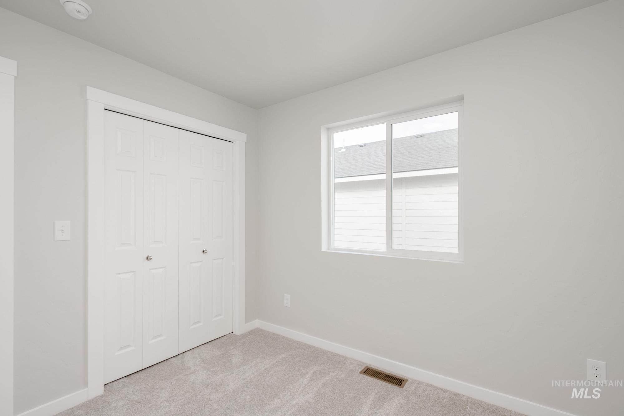 Unfurnished bedroom featuring light carpet and a closet