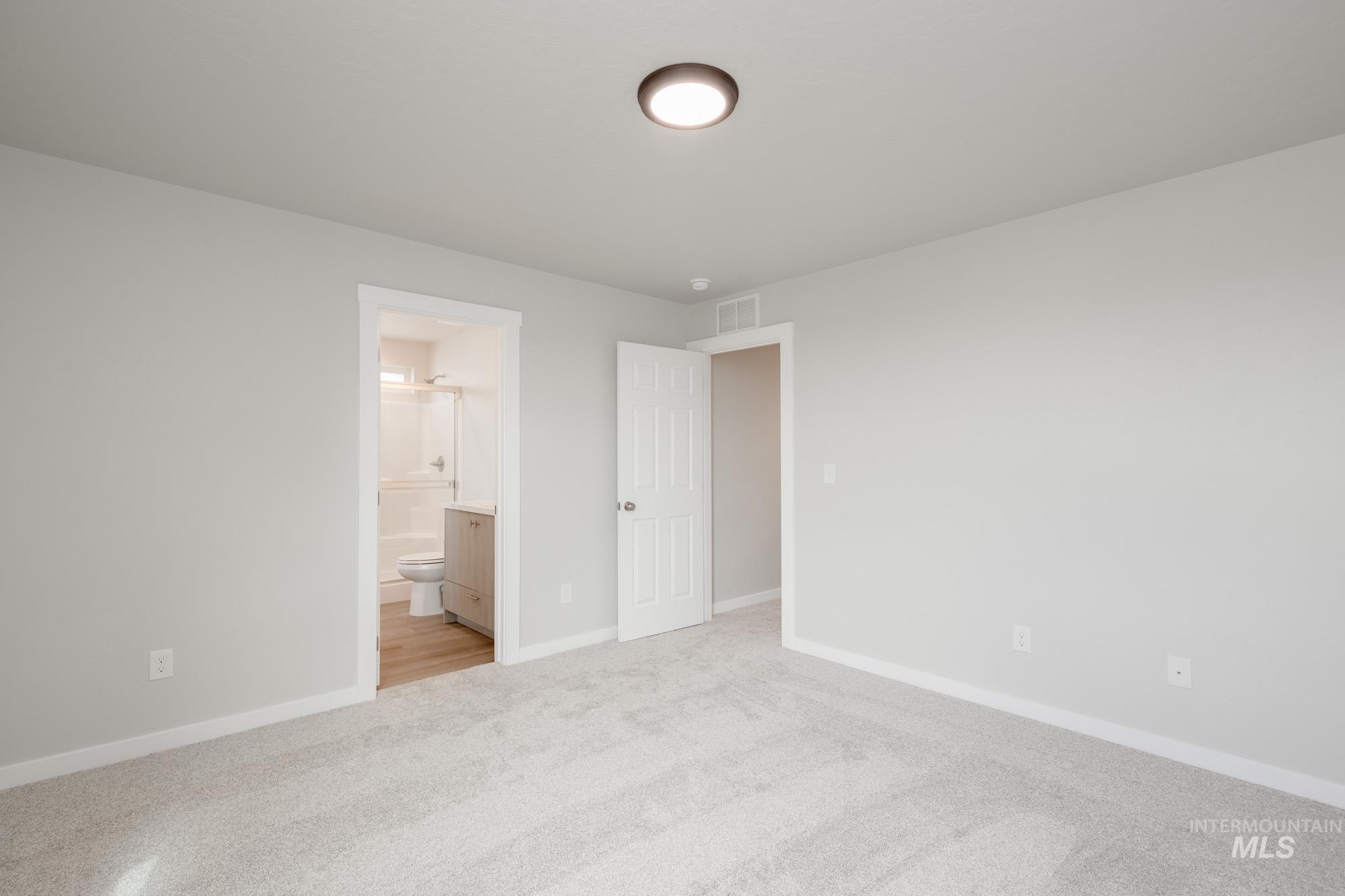 Unfurnished bedroom with light carpet and connected bathroom