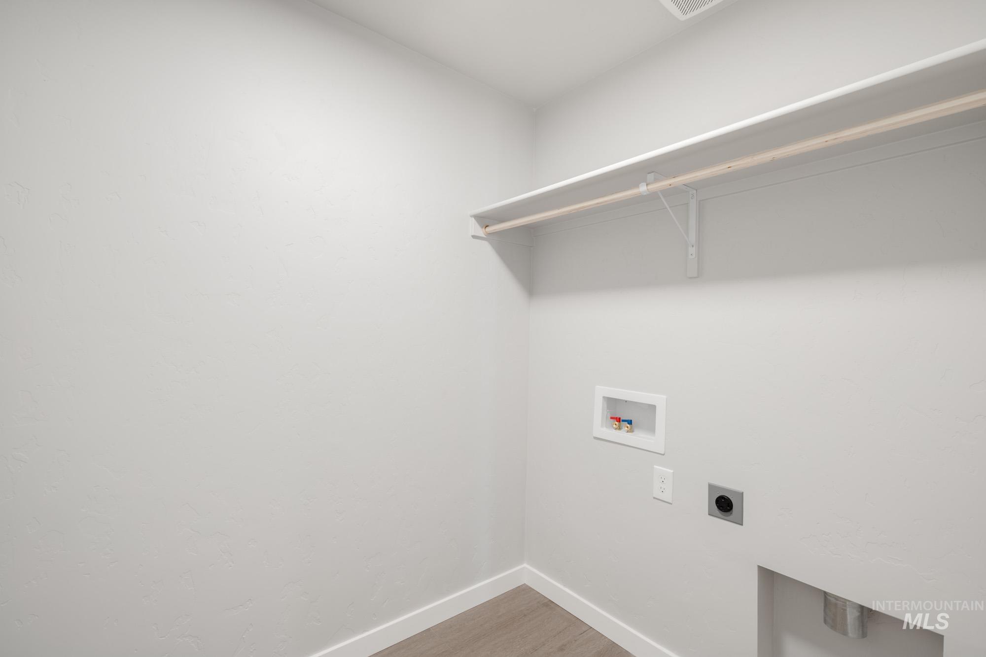 Washroom with light wood-type flooring, electric dryer hookup, and hookup for a washing machine