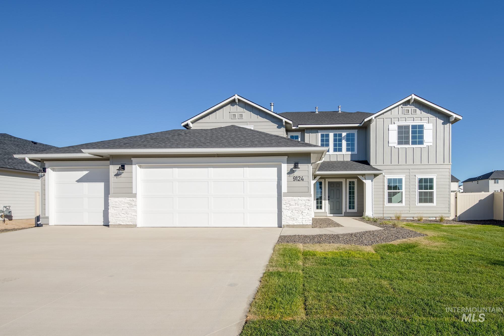 View of front of home featuring stone siding, board and batten siding, a shingled roof, and concrete driveway