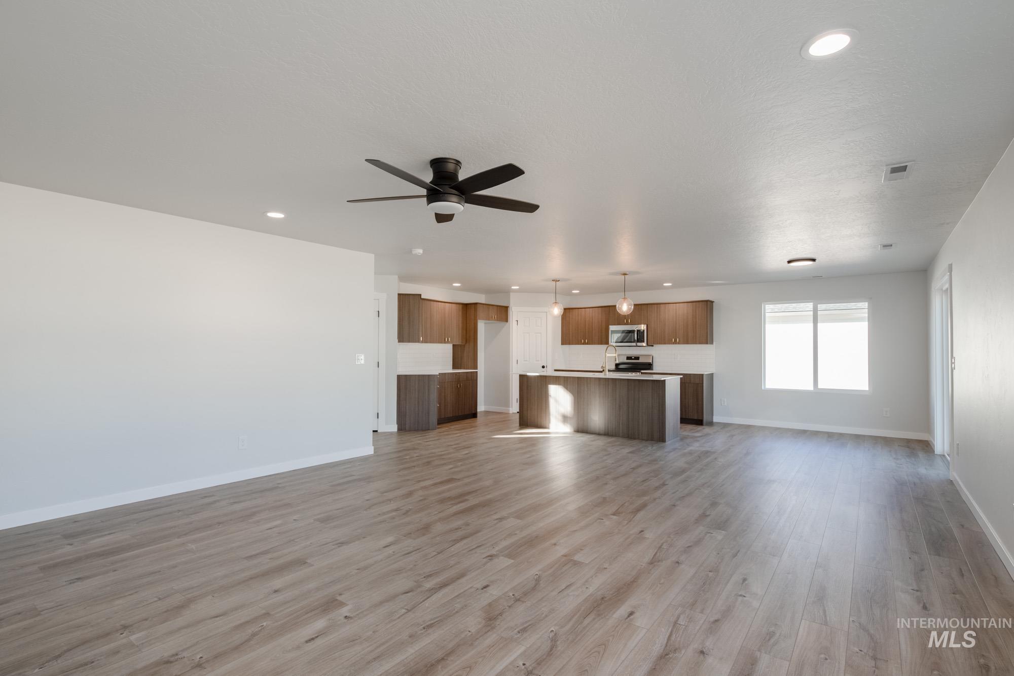 Unfurnished living room with light wood-style floors, recessed lighting, and a ceiling fan