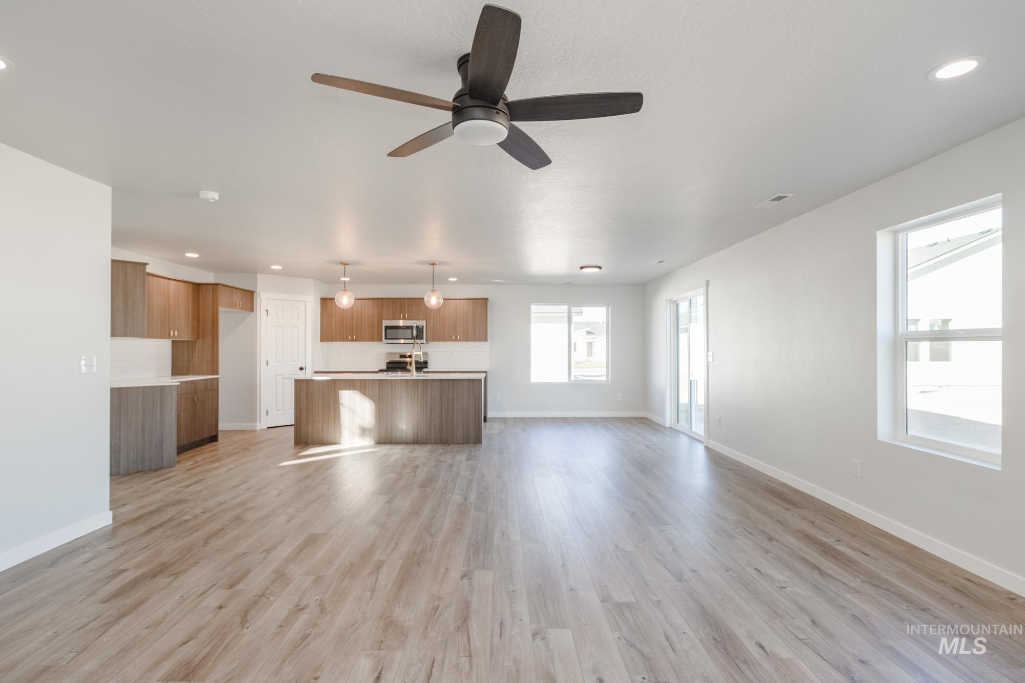 Unfurnished living room featuring light wood-type flooring, a ceiling fan, and recessed lighting