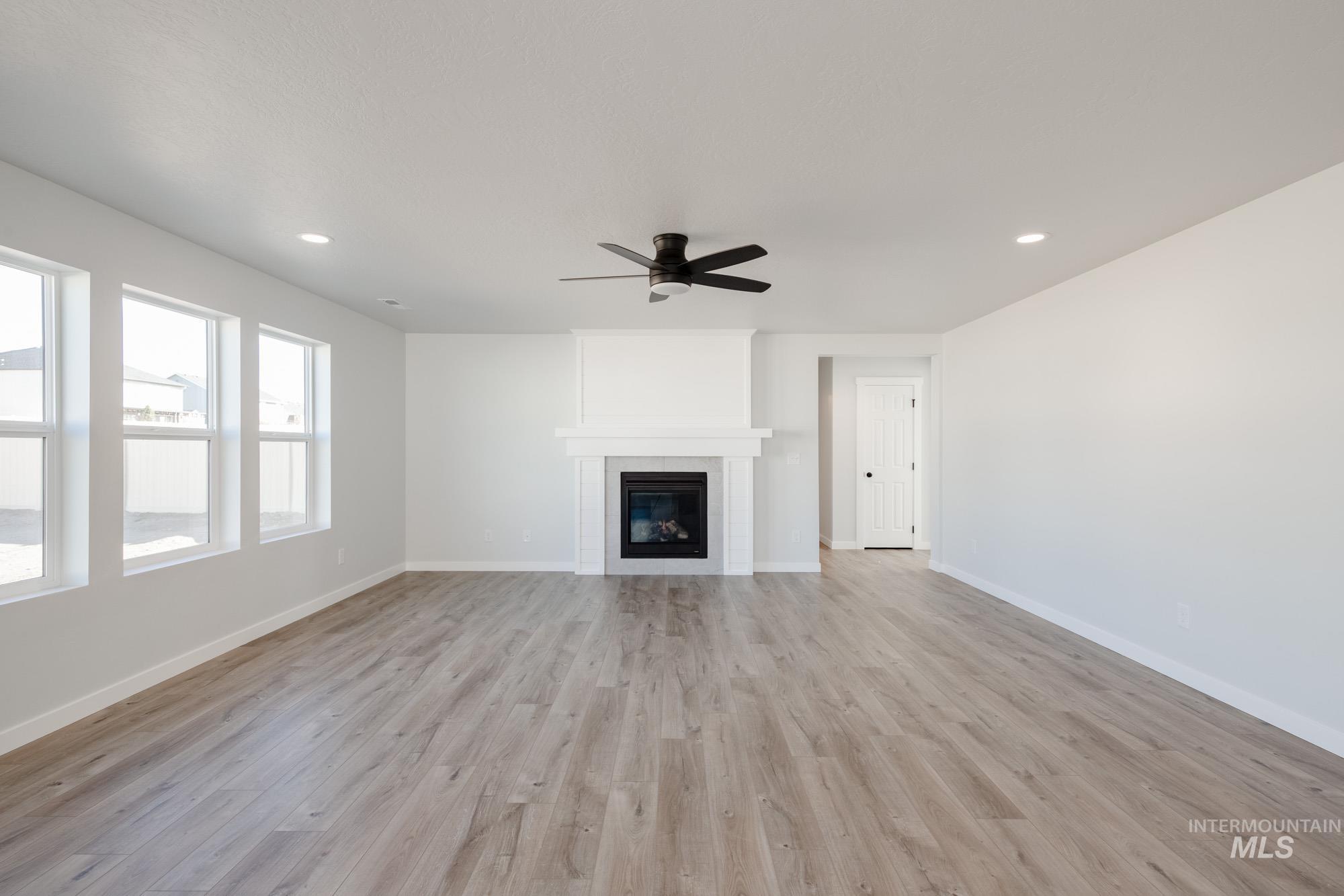 Unfurnished living room with light wood-style flooring, recessed lighting, a large fireplace, and ceiling fan