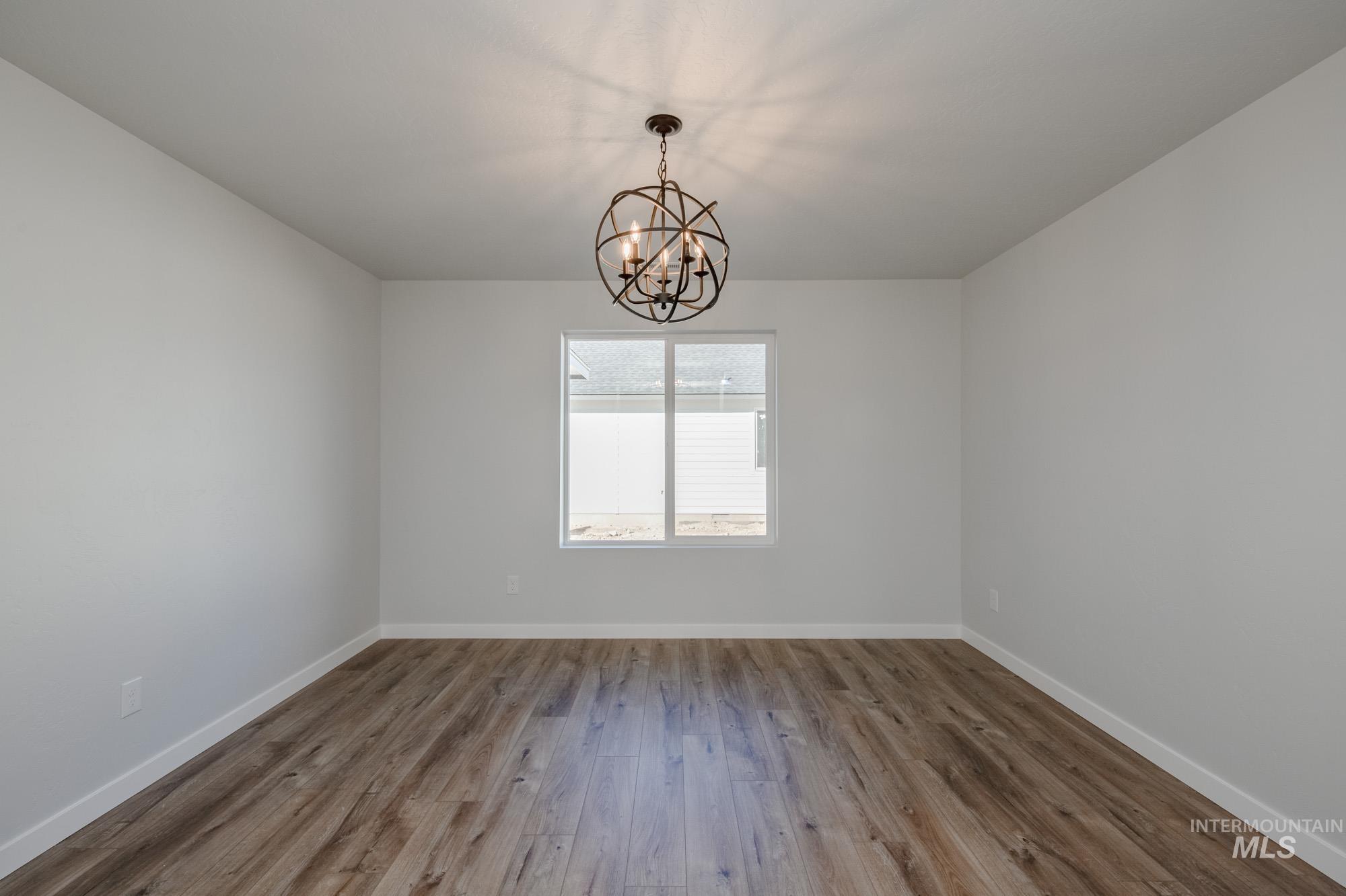 Spare room featuring wood finished floors and a chandelier