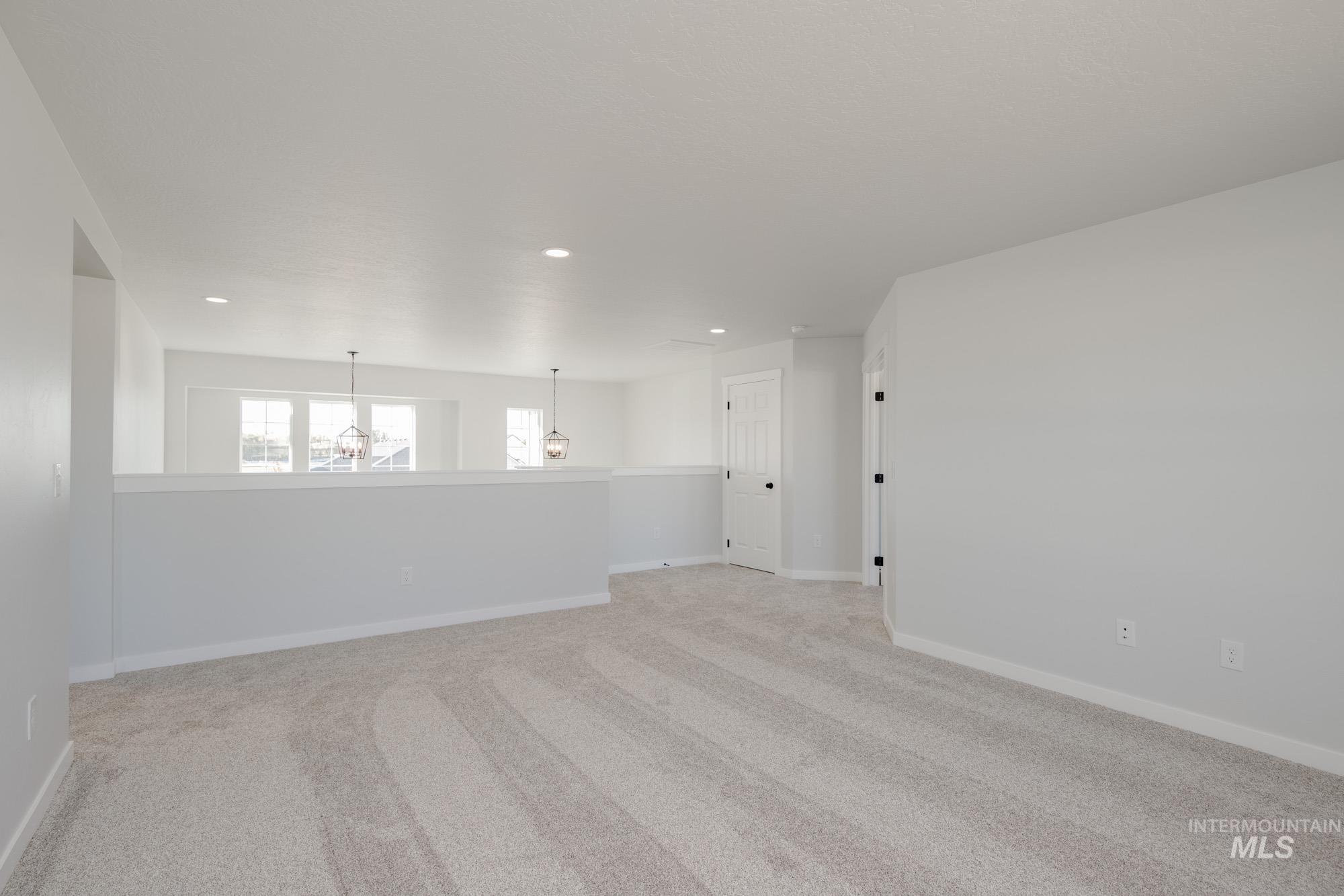 Empty room with light colored carpet, recessed lighting, and a chandelier