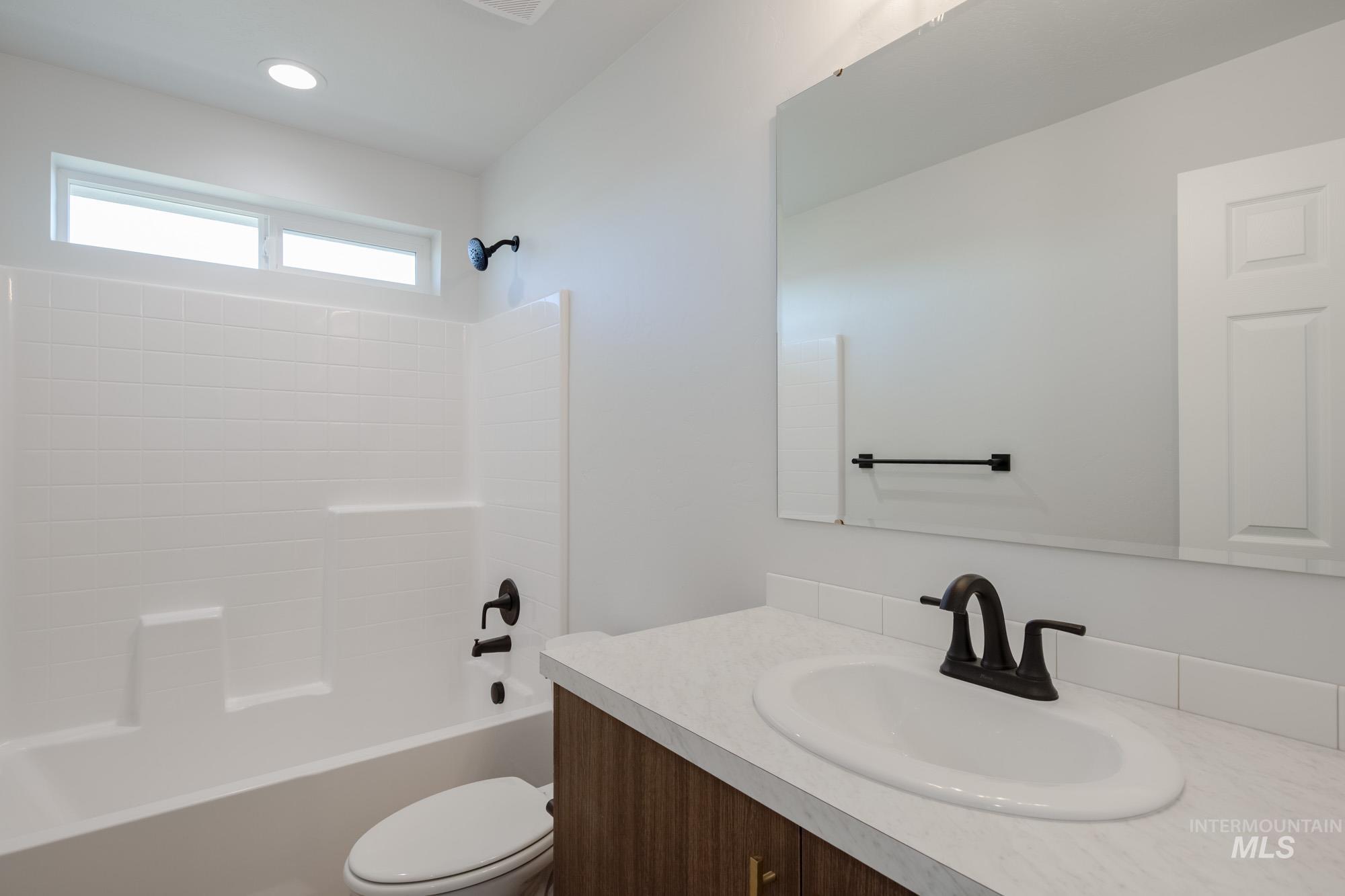 Bathroom with washtub / shower combination, vanity, and recessed lighting
