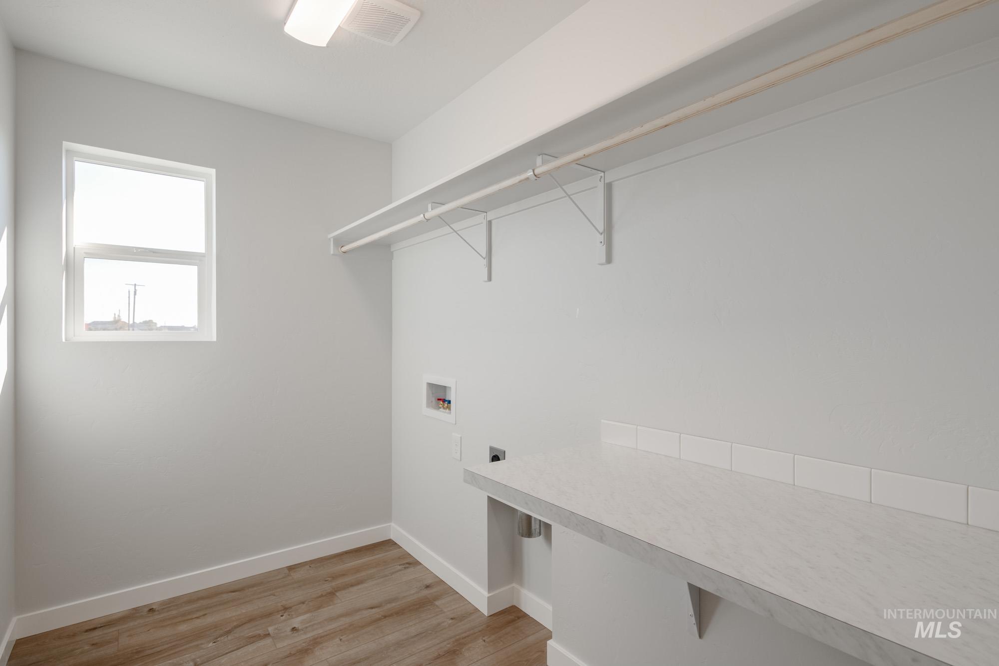Laundry area with light wood-style floors, washer hookup, and hookup for an electric dryer