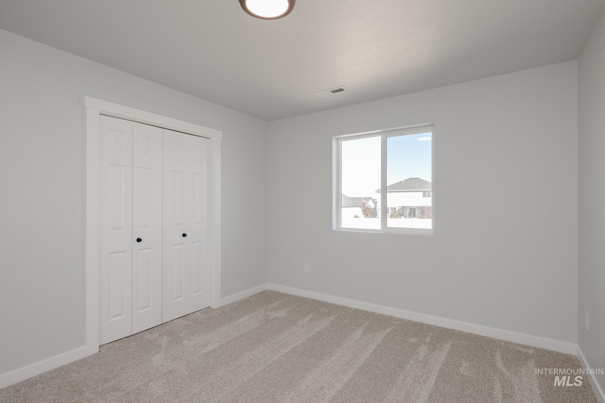 Unfurnished bedroom featuring light carpet and a closet
