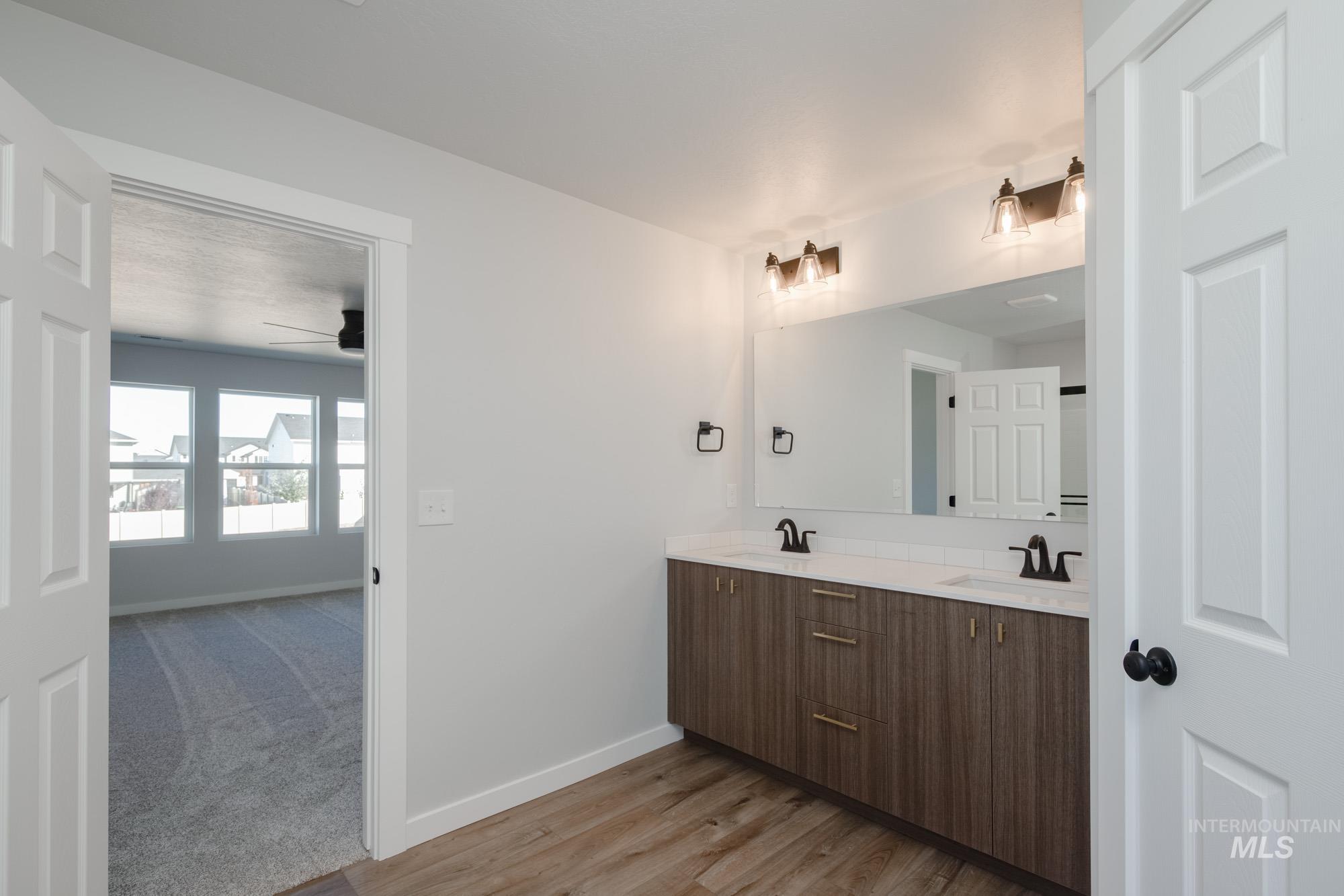 Bathroom with double vanity, light wood-type flooring, a ceiling fan, and light colored carpet