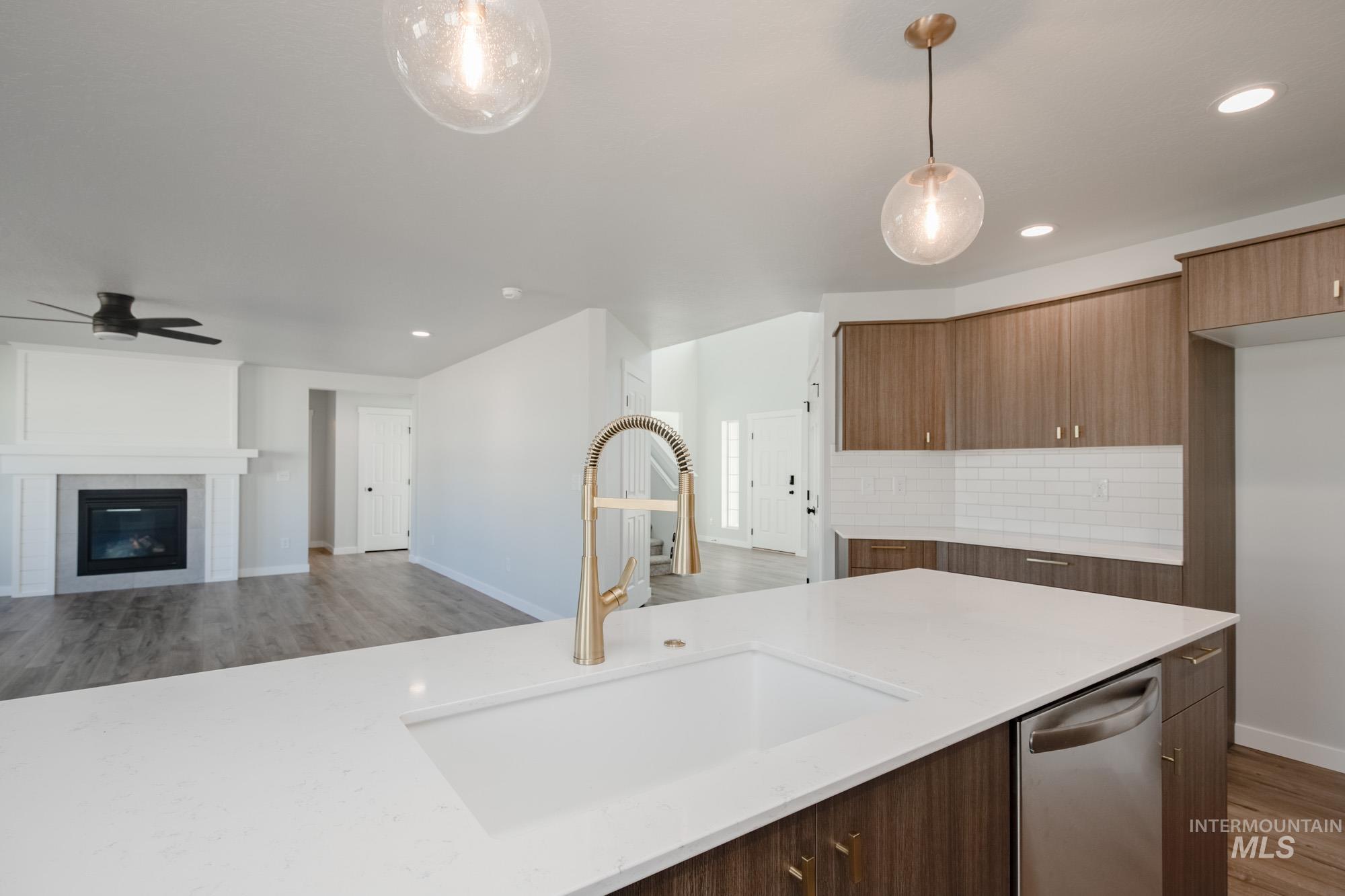Kitchen with light wood-style flooring, open floor plan, pendant lighting, light stone counters, and tasteful backsplash