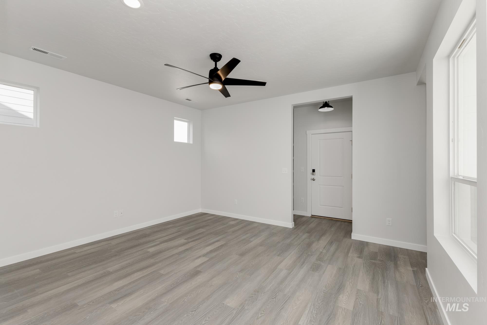 Empty room with plenty of natural light, light wood-type flooring, and a ceiling fan