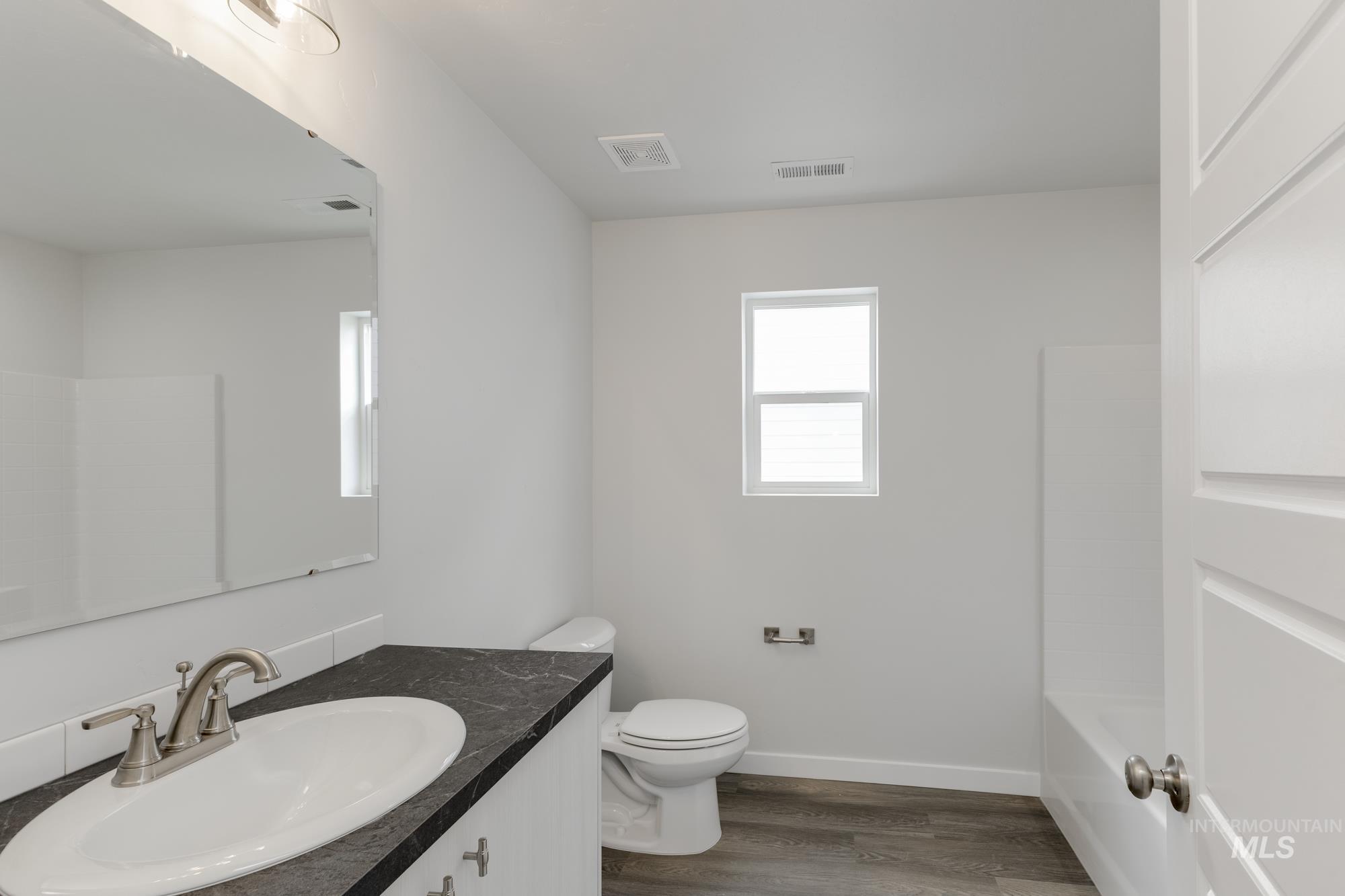 Full bathroom featuring dark wood finished floors, vanity, and tub / shower combination