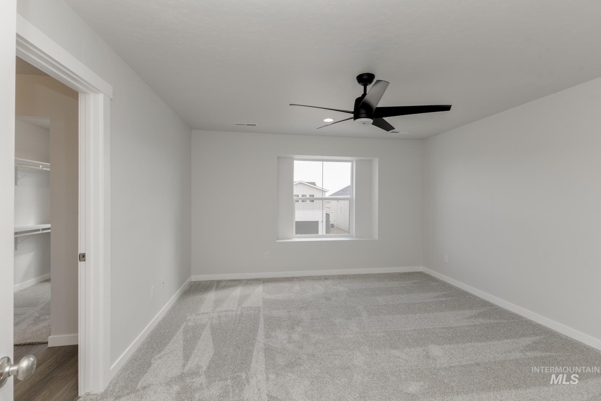 Unfurnished bedroom with light carpet, a spacious closet, and ceiling fan