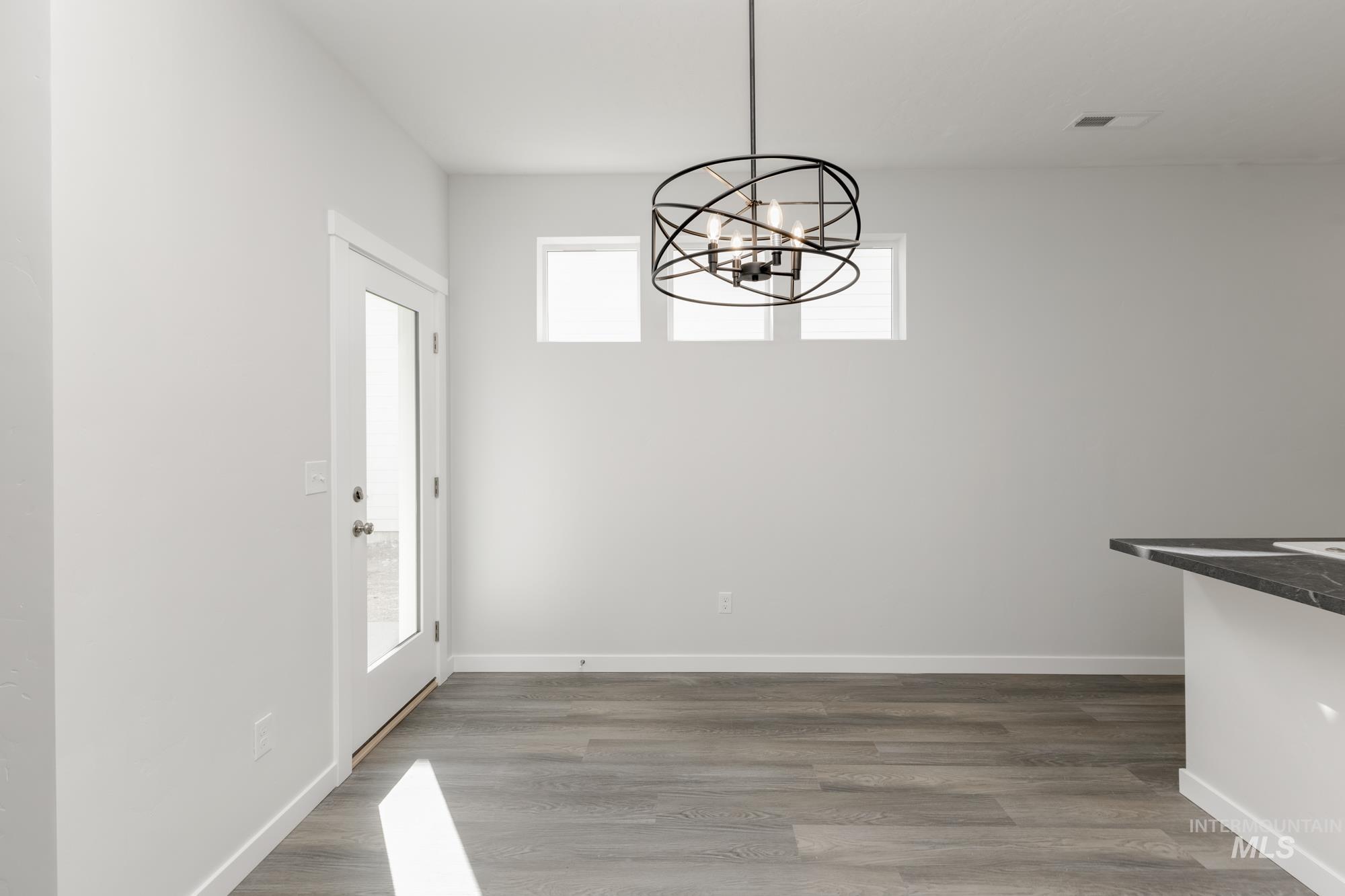 Unfurnished dining area with wood finished floors and a chandelier
