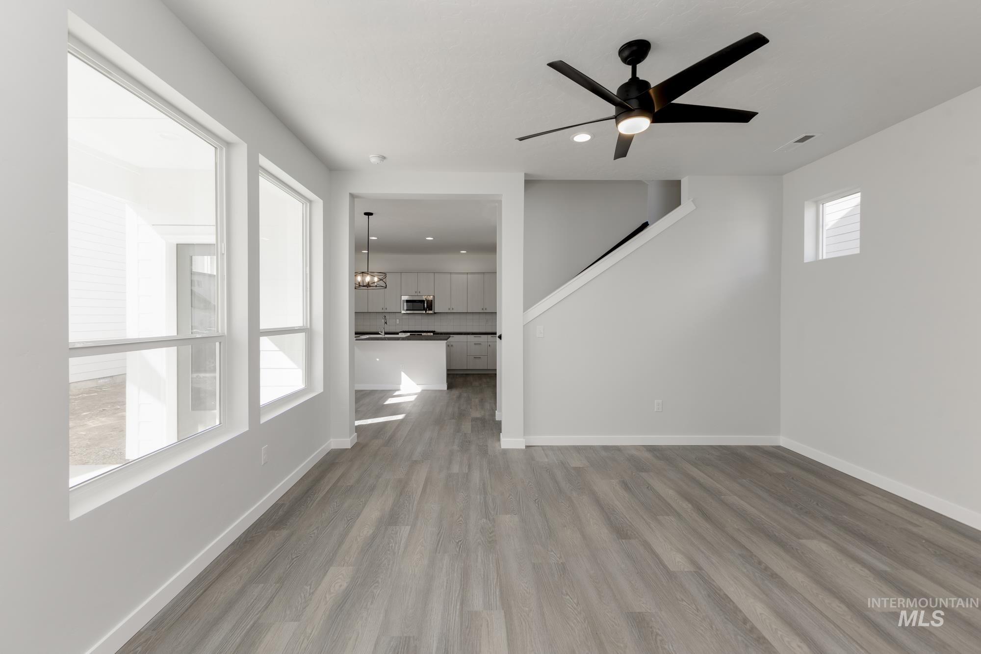 Unfurnished living room with dark wood-style flooring, a ceiling fan, recessed lighting, and a chandelier