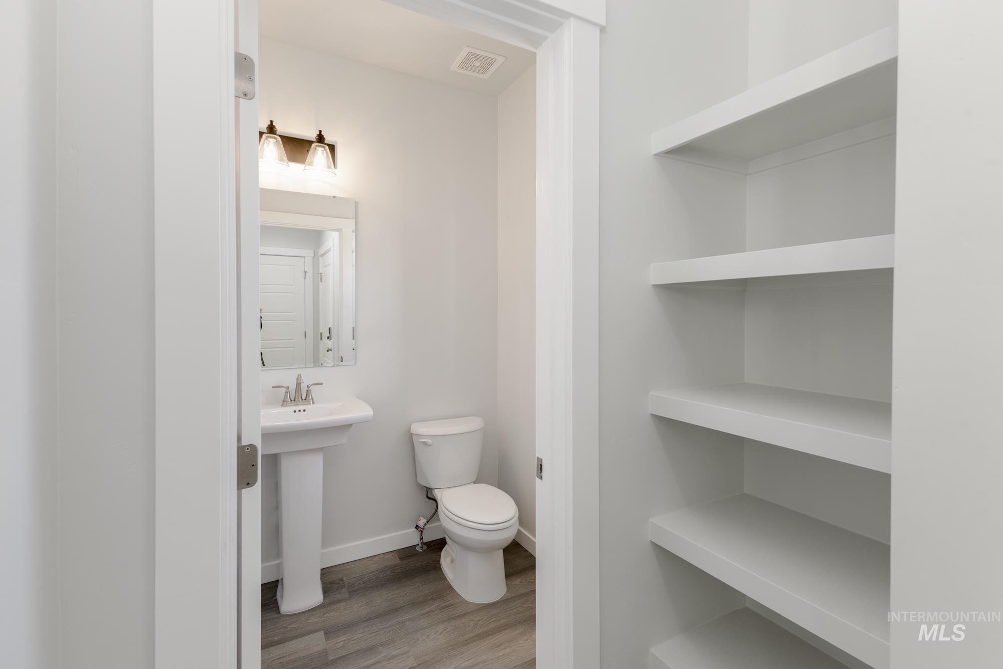 Half bath with light wood-type flooring and toilet
