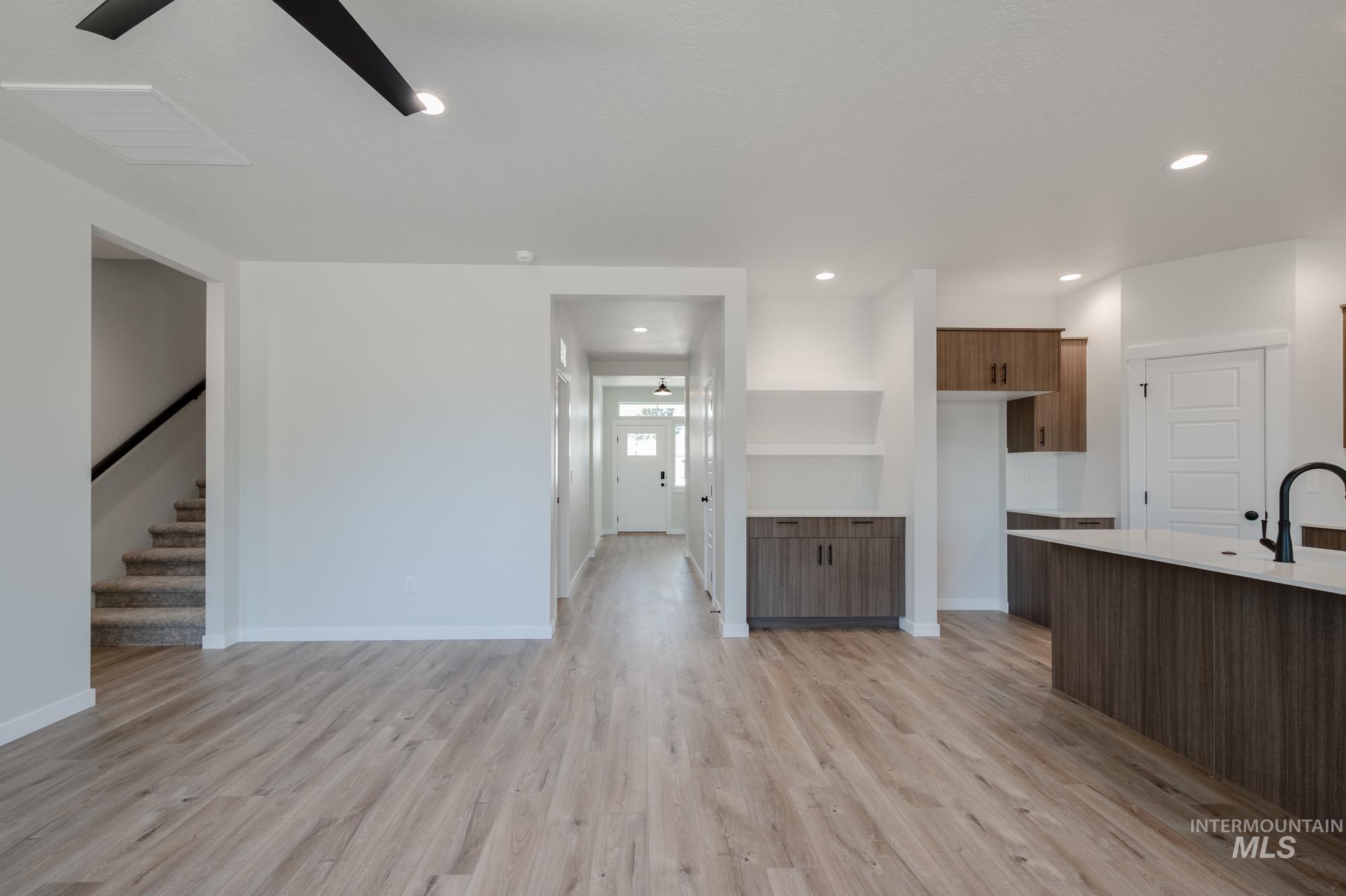 Kitchen featuring light wood-style floors, modern cabinets, light stone counters, recessed lighting, and open shelves