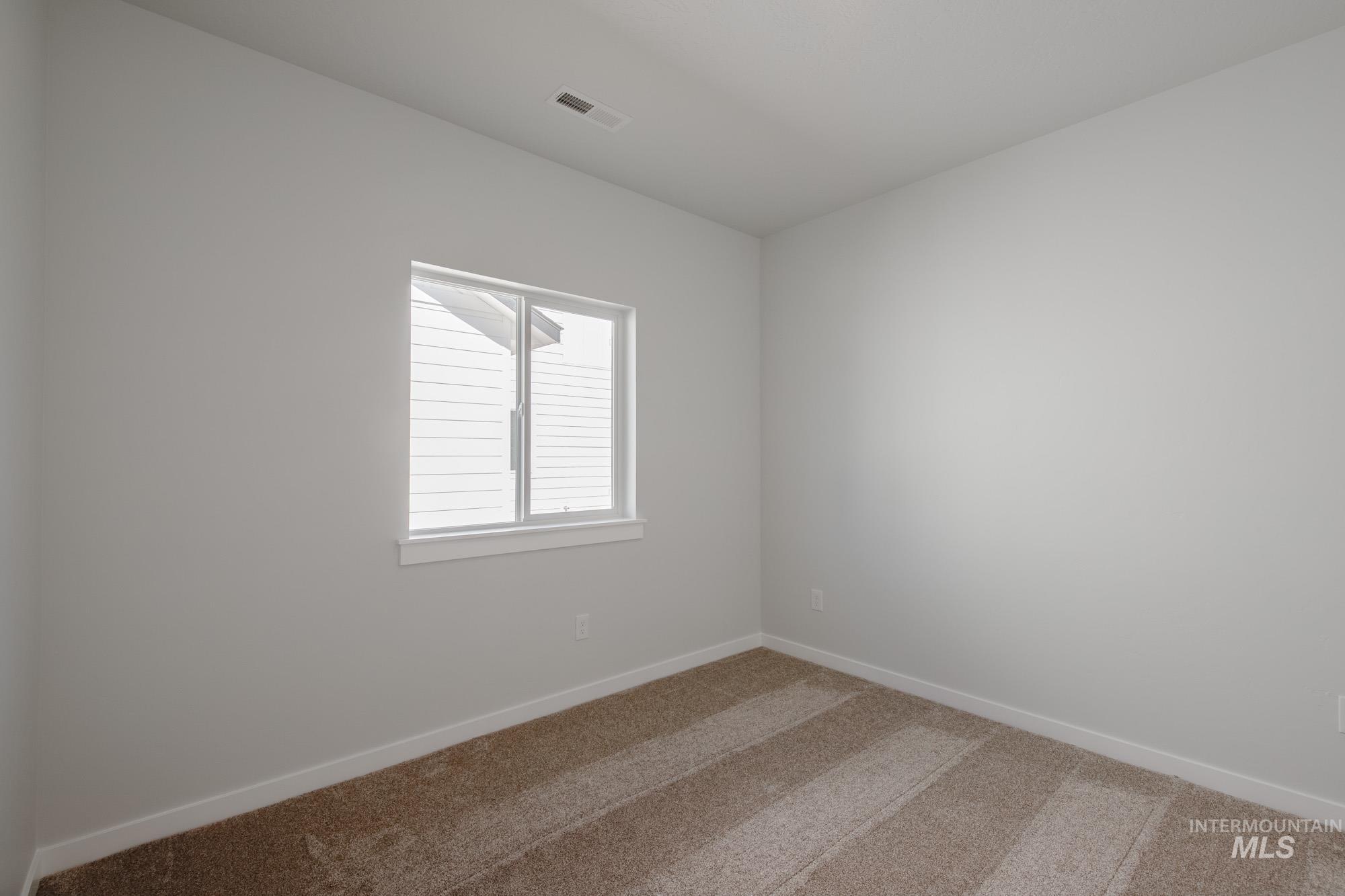 Carpeted spare room featuring baseboards