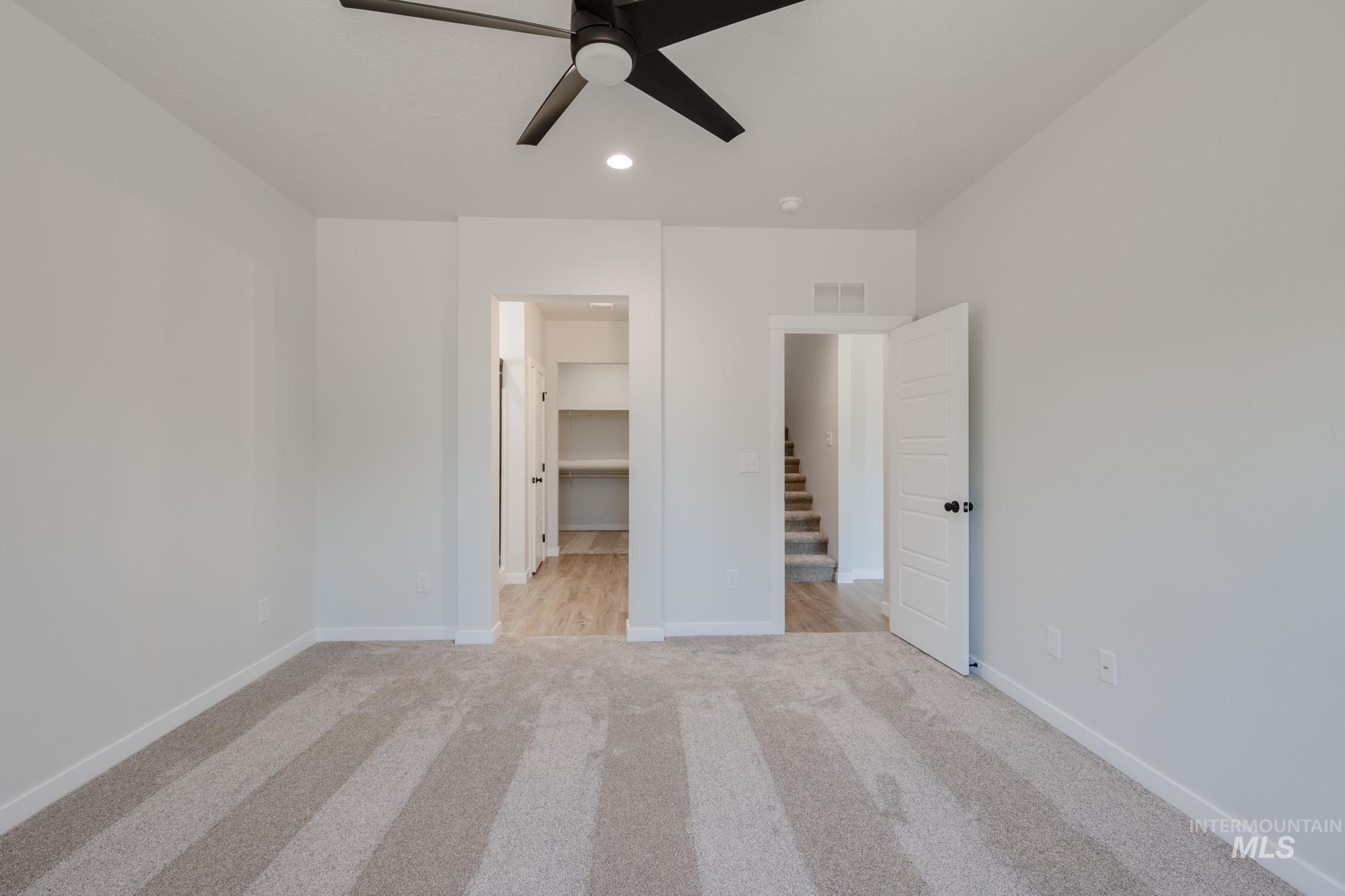 Unfurnished bedroom featuring light carpet, a walk in closet, a ceiling fan, and recessed lighting