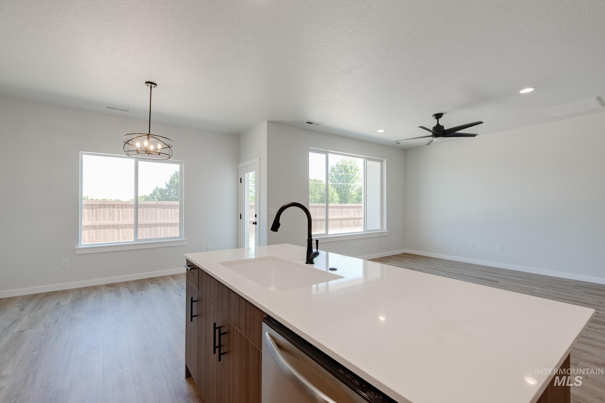 Kitchen featuring light wood-style floors, open floor plan, hanging light fixtures, dishwasher, and a chandelier