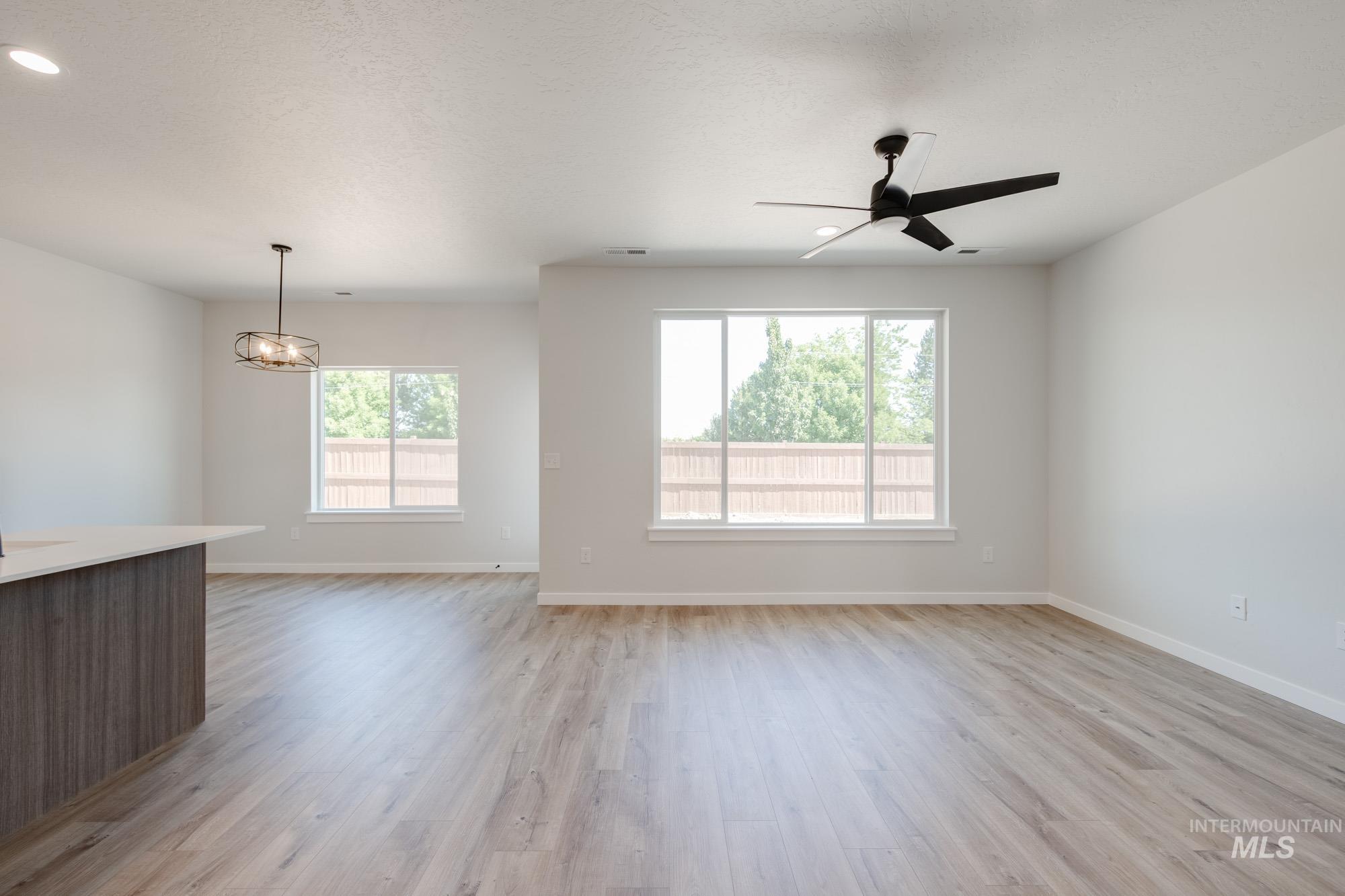 Unfurnished living room with plenty of natural light, light wood finished floors, a ceiling fan, a textured ceiling, and recessed lighting