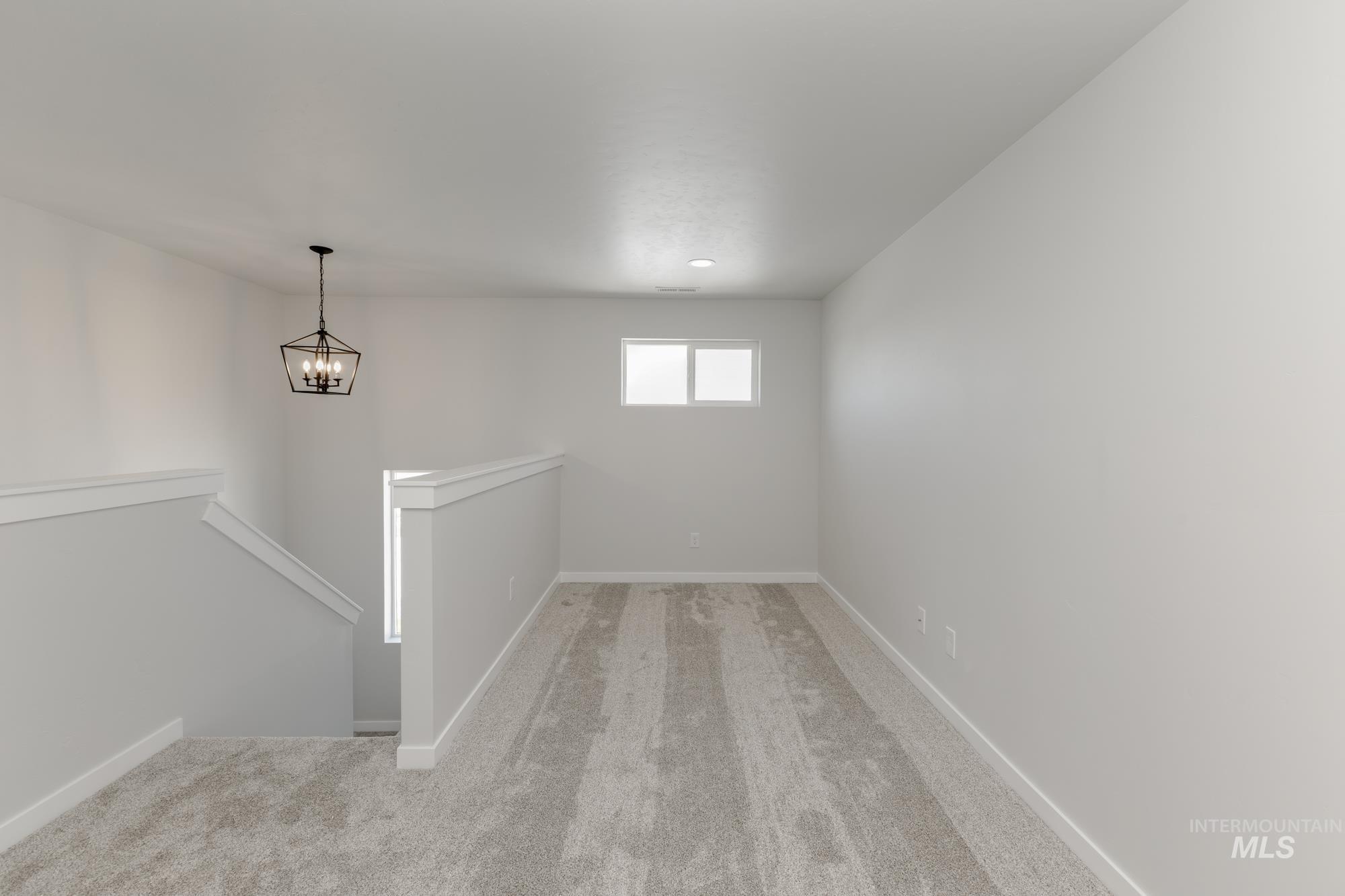 Unfurnished room with light colored carpet and a chandelier