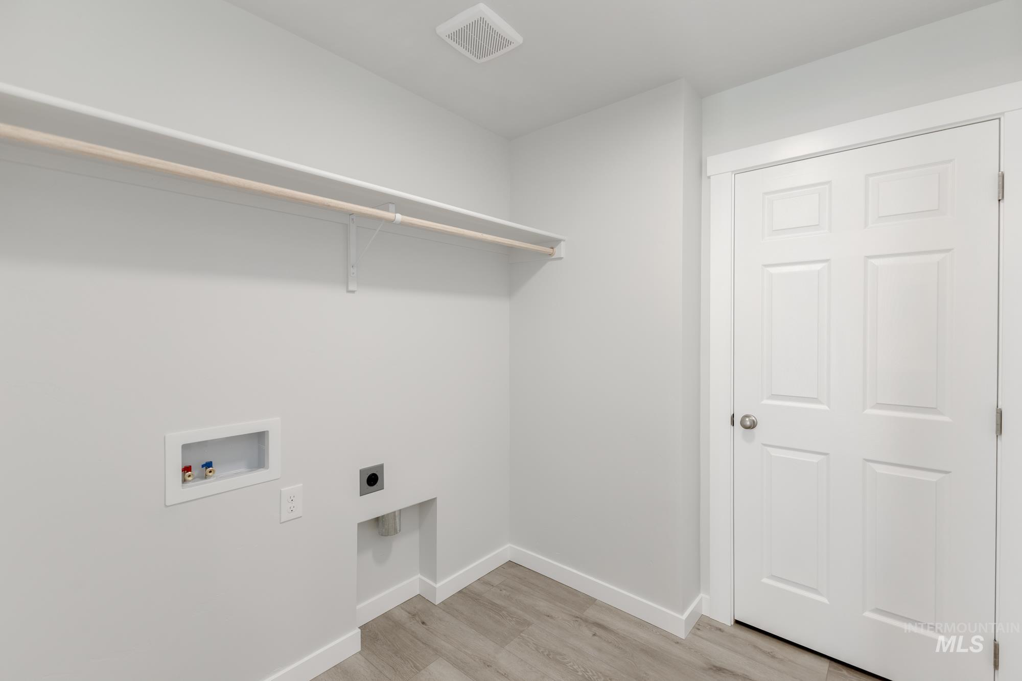 Laundry area featuring electric dryer hookup, light wood-style floors, and washer hookup
