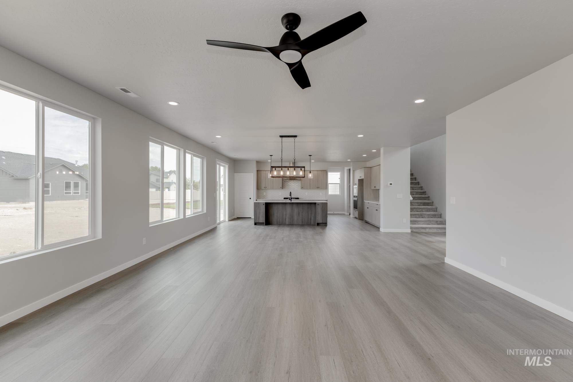 Unfurnished living room with recessed lighting, light wood-type flooring, stairway, and a ceiling fan