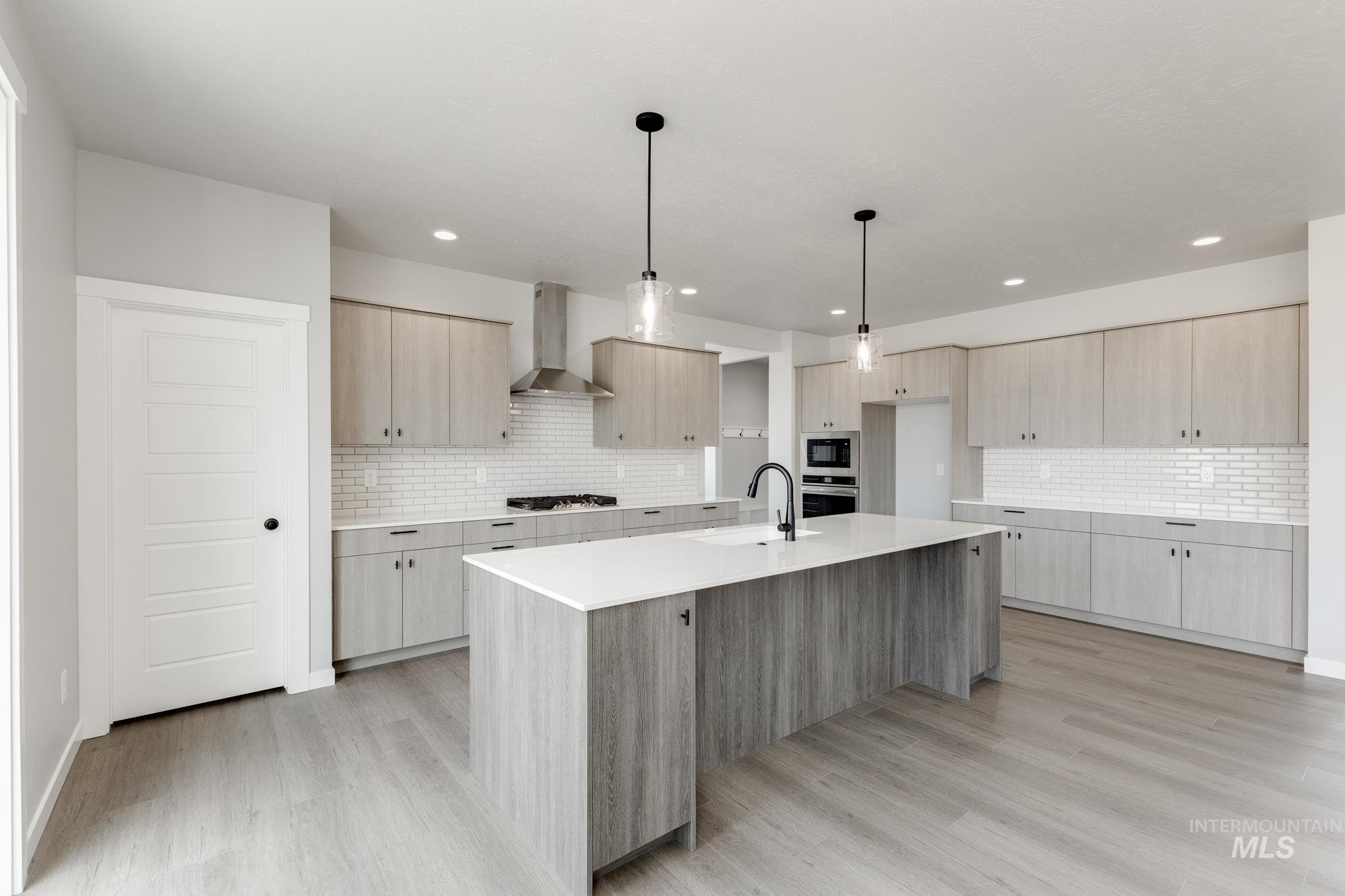 Kitchen featuring an island with sink, light brown cabinets, hanging light fixtures, modern cabinets, and recessed lighting