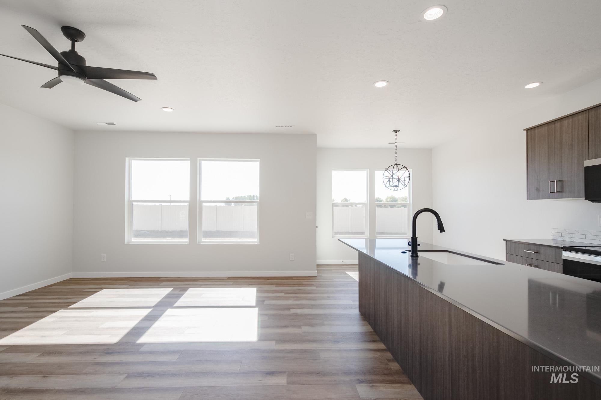 Kitchen featuring modern cabinets, recessed lighting, light wood-type flooring, pendant lighting, and light stone counters