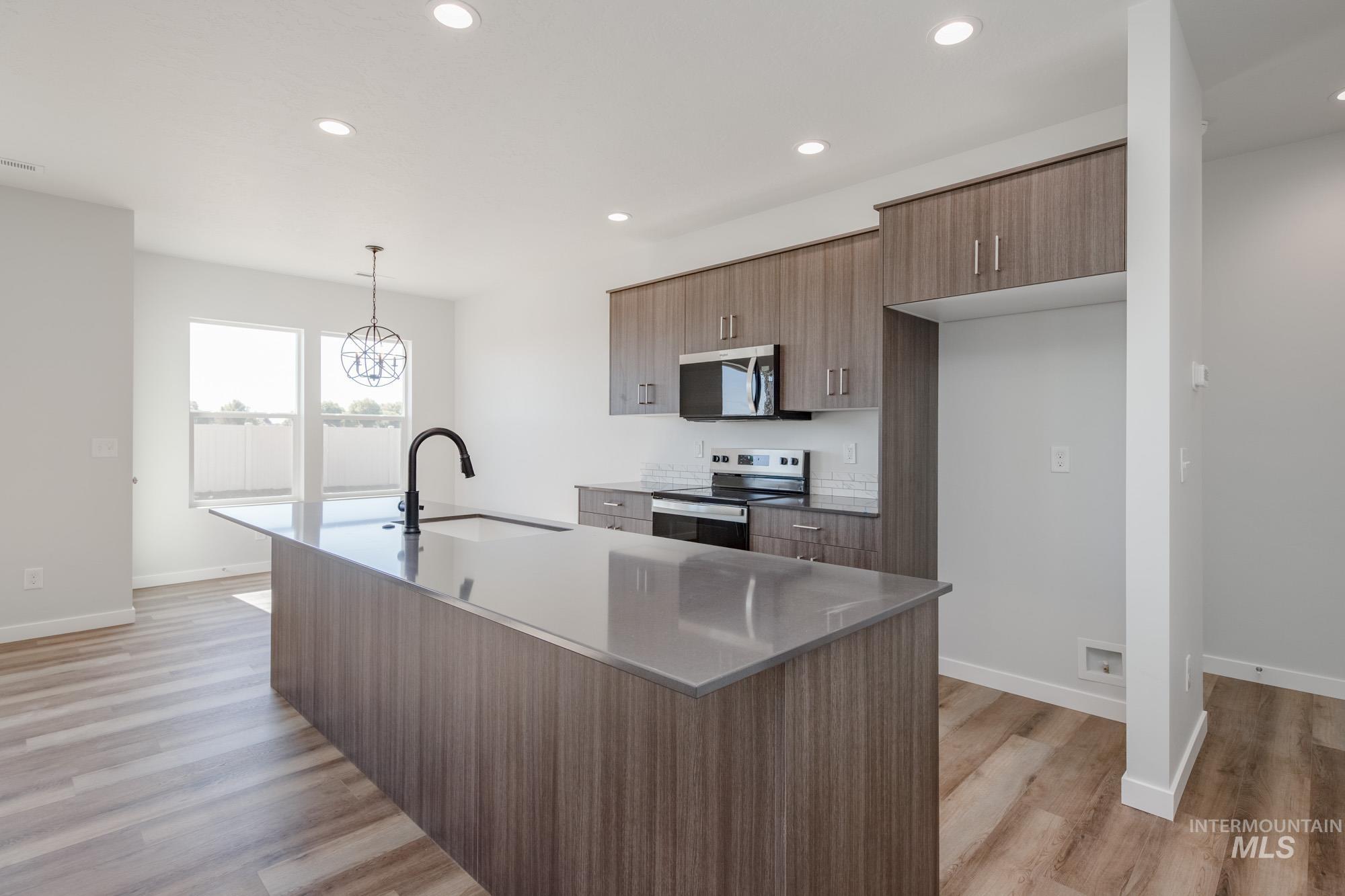 Kitchen with recessed lighting, appliances with stainless steel finishes, modern cabinets, light wood-style flooring, and hanging light fixtures