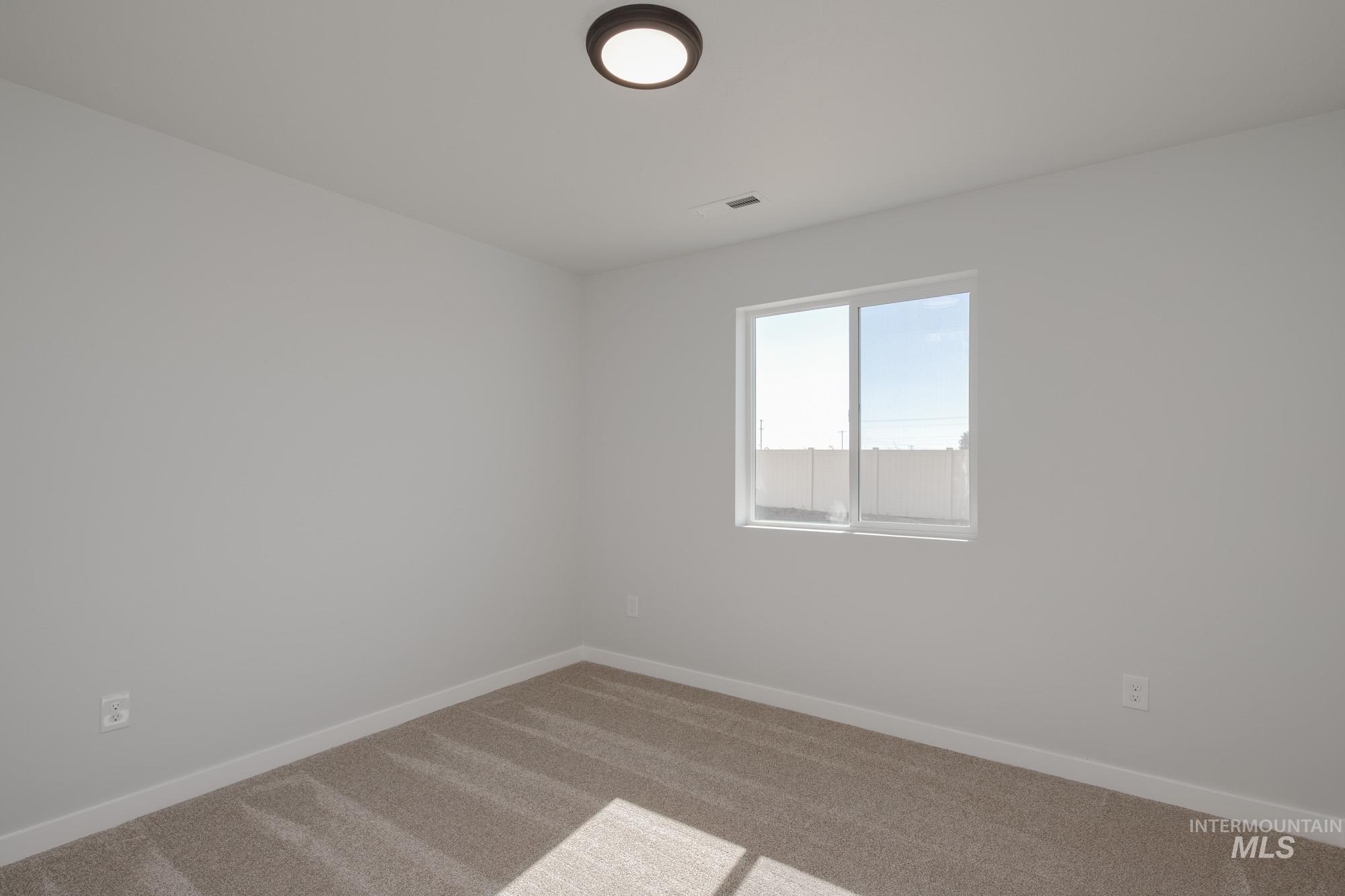 Carpeted spare room featuring baseboards