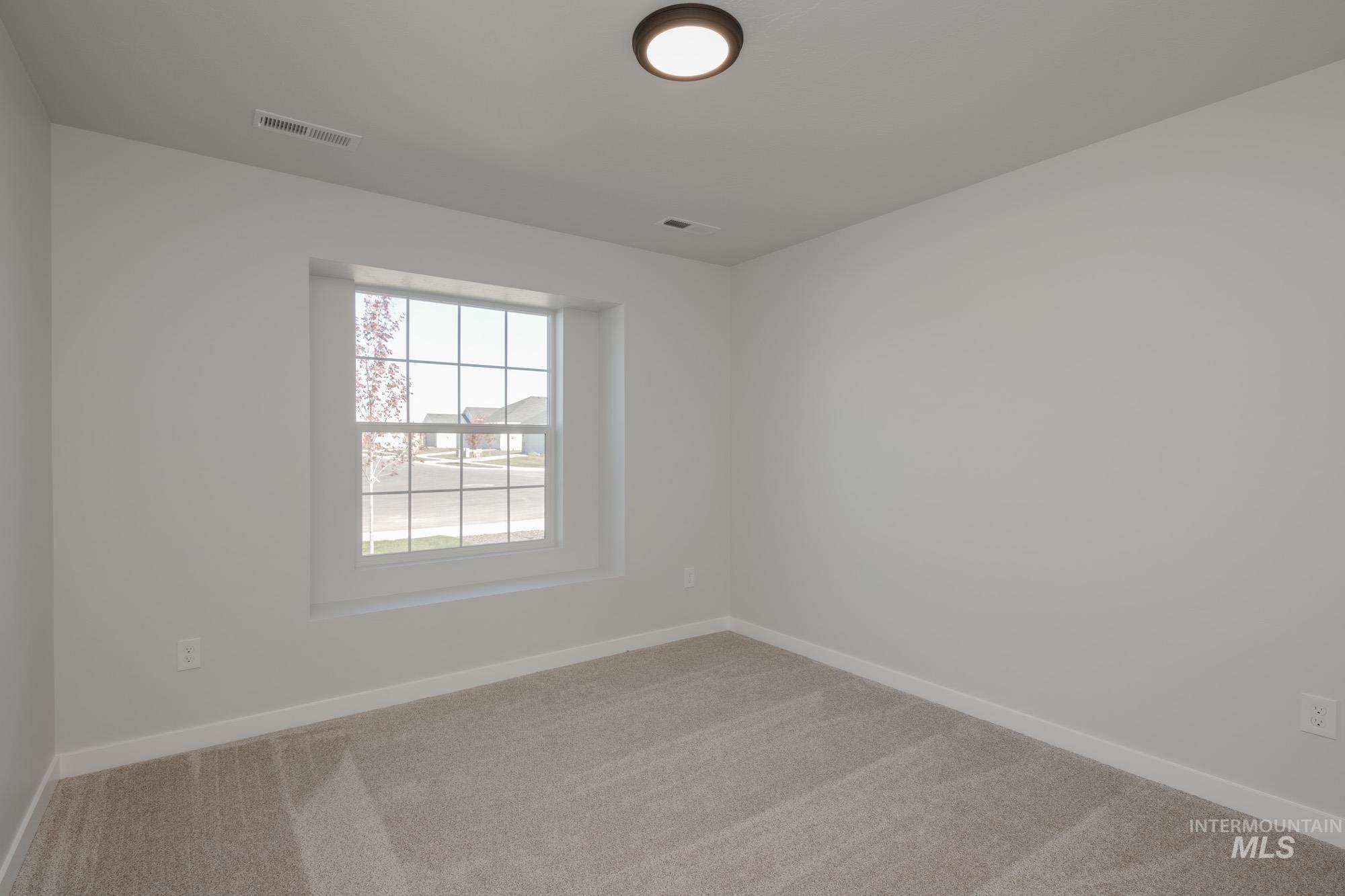 Empty room featuring light colored carpet and baseboards